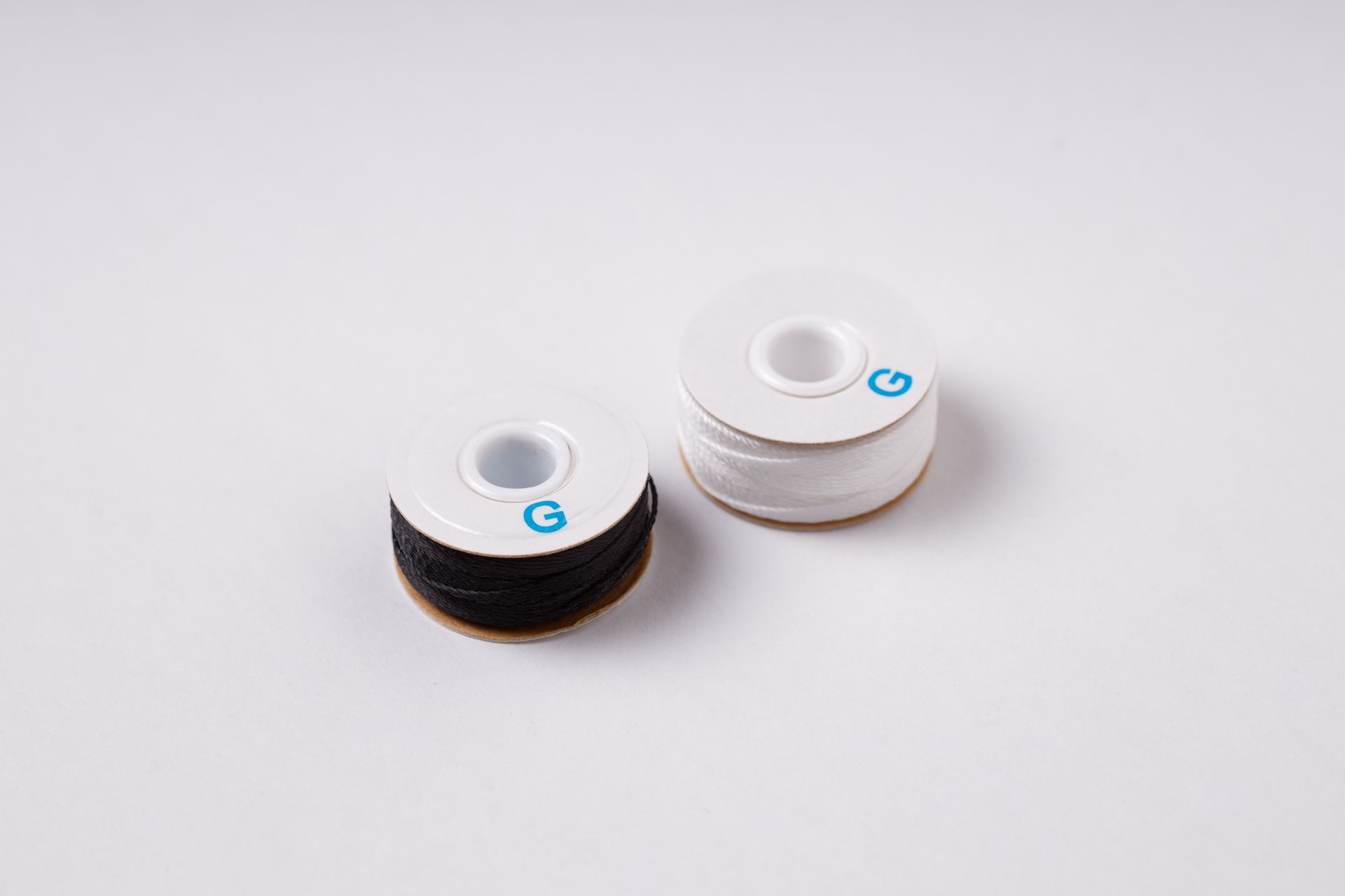 Two spools of thread are sitting on a white surface.