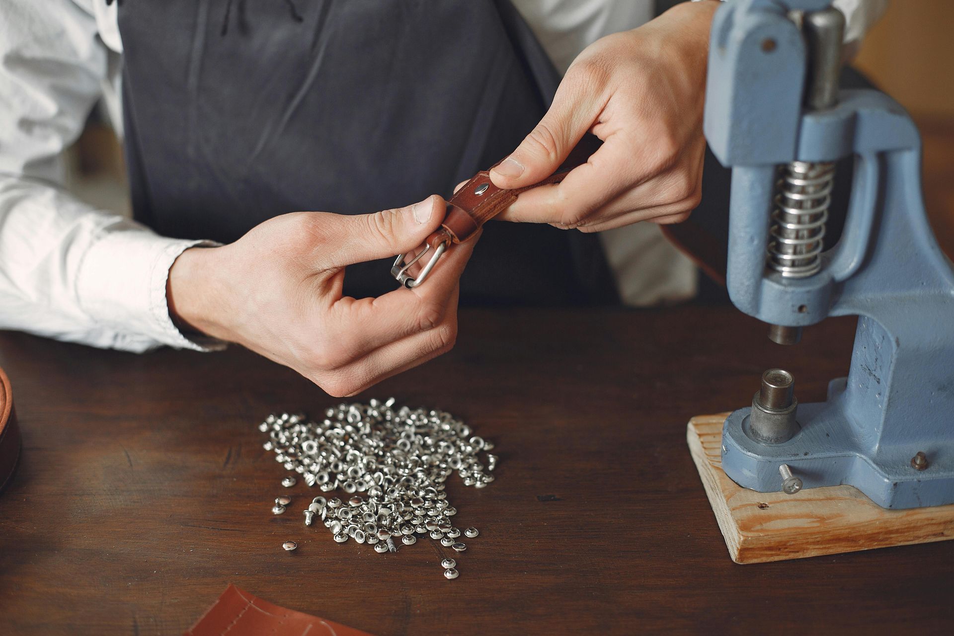 A man is using a machine to make a piece of jewelry.