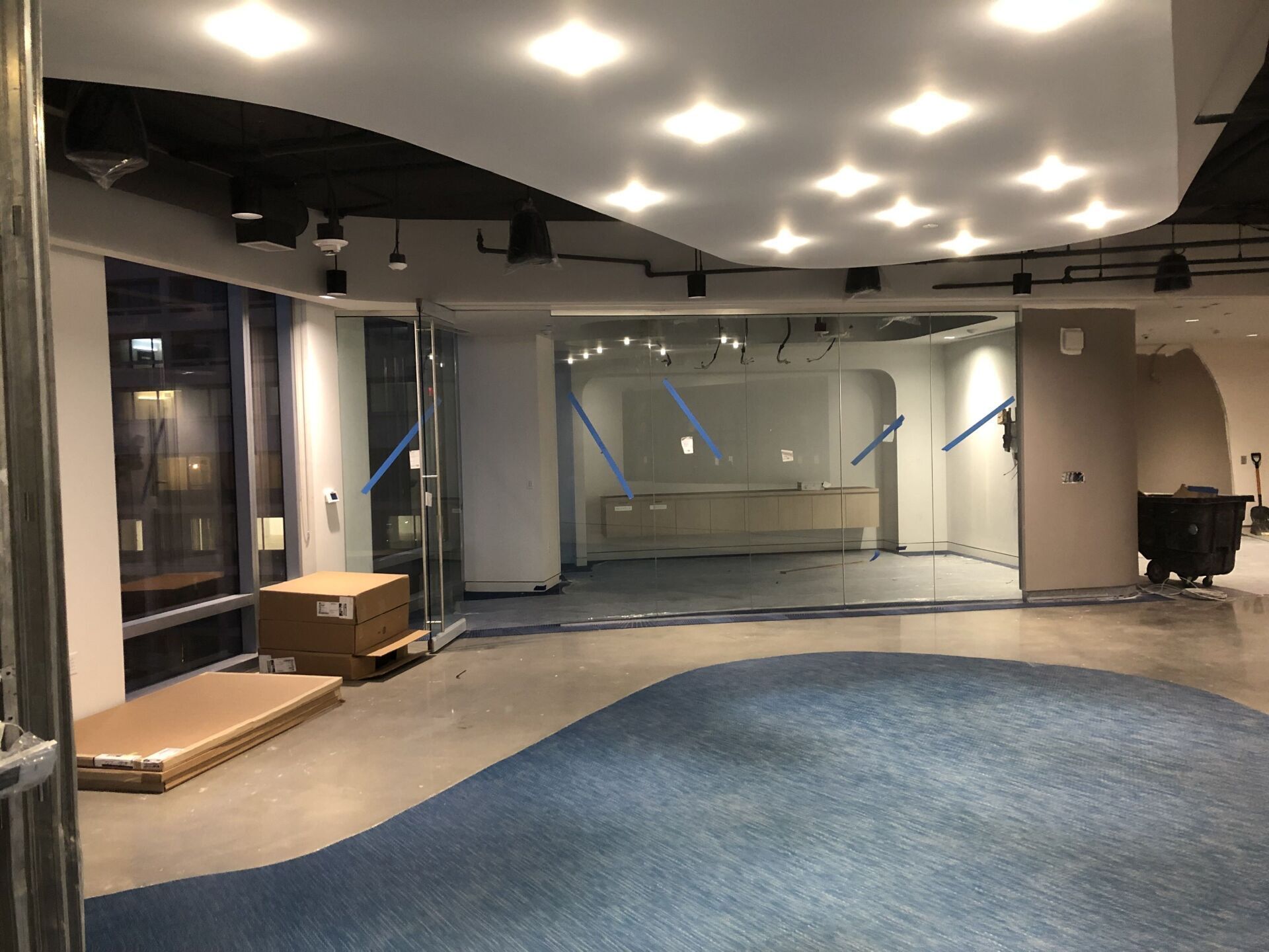 A large empty room with a blue carpet and a glass wall.