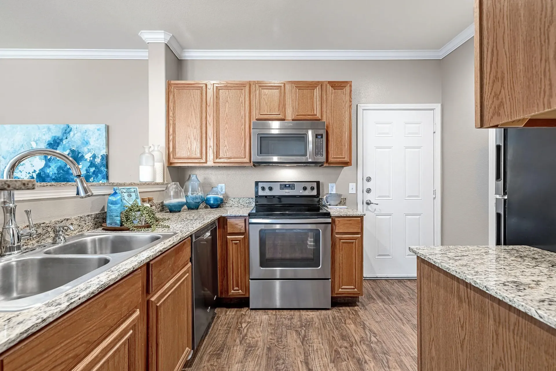 Modern kitchen with stainless steel appliances, granite countertops, and wood cabinets.