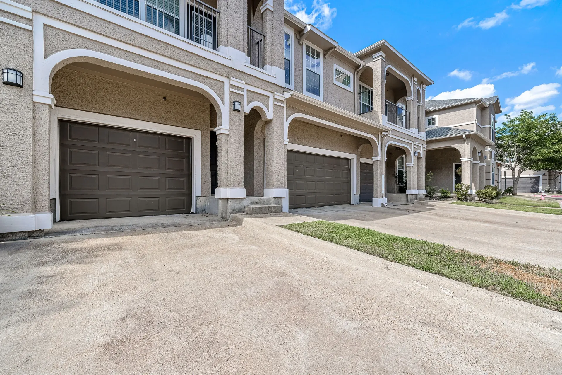 Townhouse-style apartment buildings with attached garages and arched entryways.