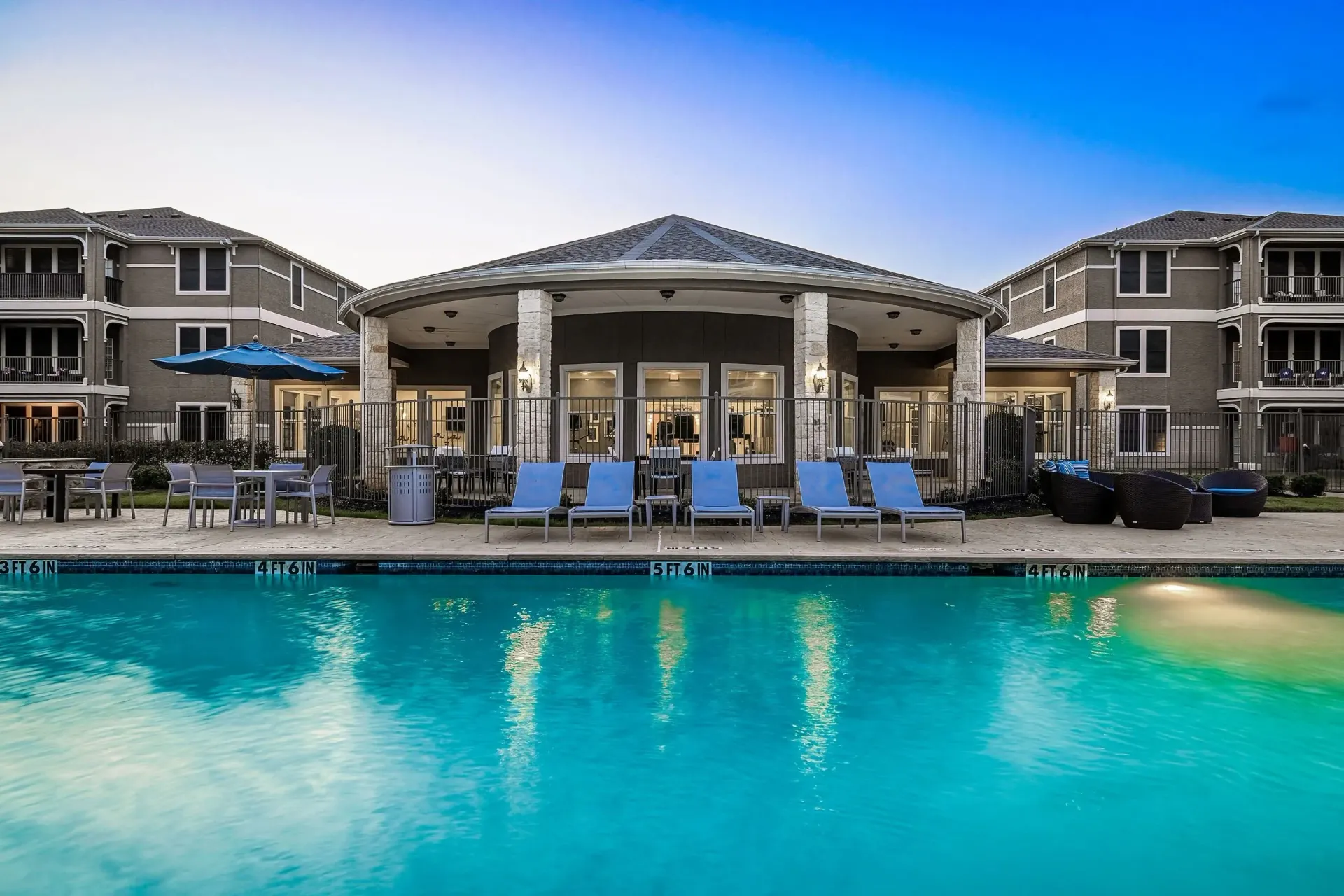 Resort-style swimming pool with lounge chairs and a clubhouse at a multifamily property.