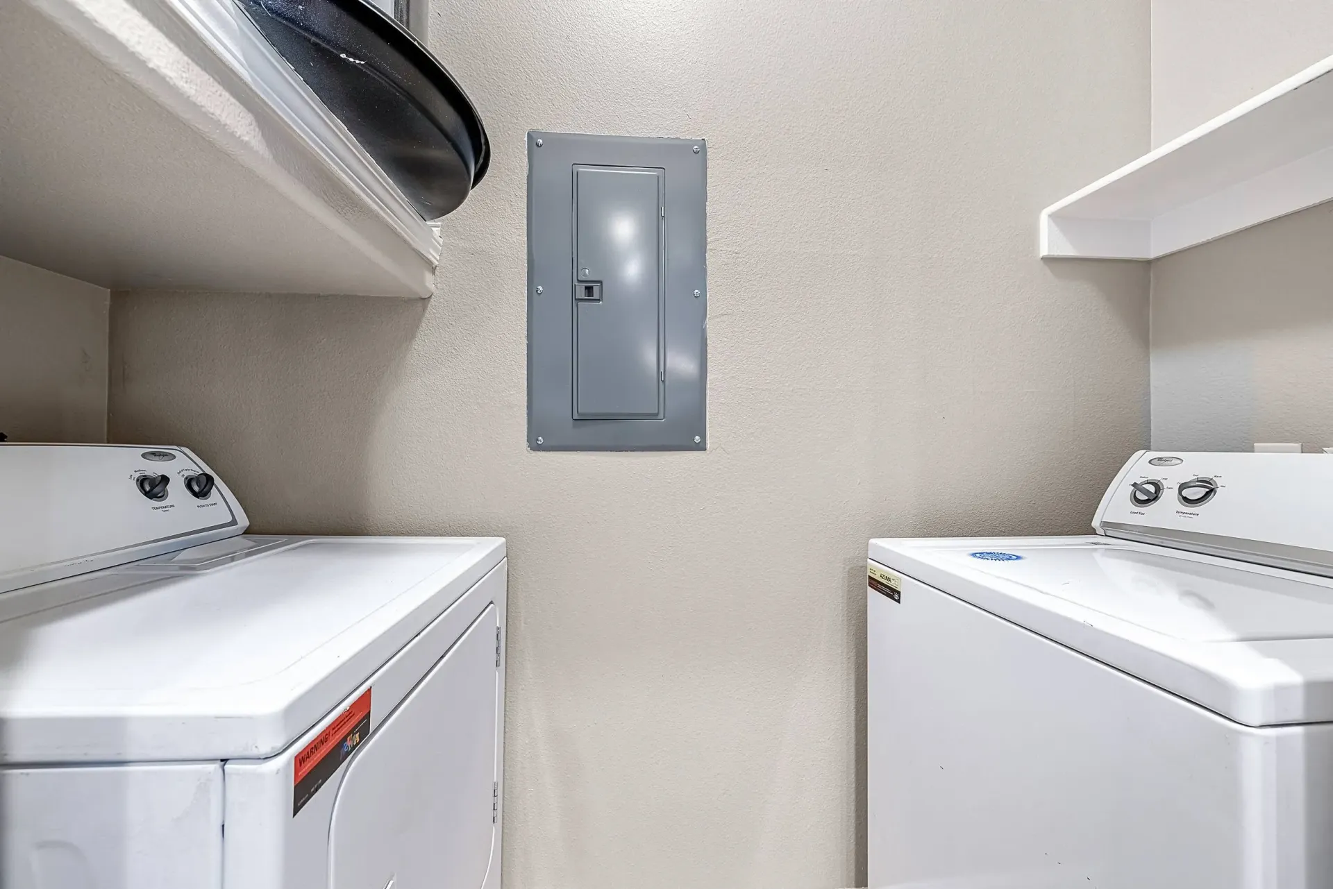 In-unit washer and dryer with a gray electrical panel on the wall.