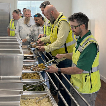 A large group of people are standing around buffet tables