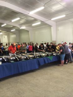 A large group of people are standing around buffet tables