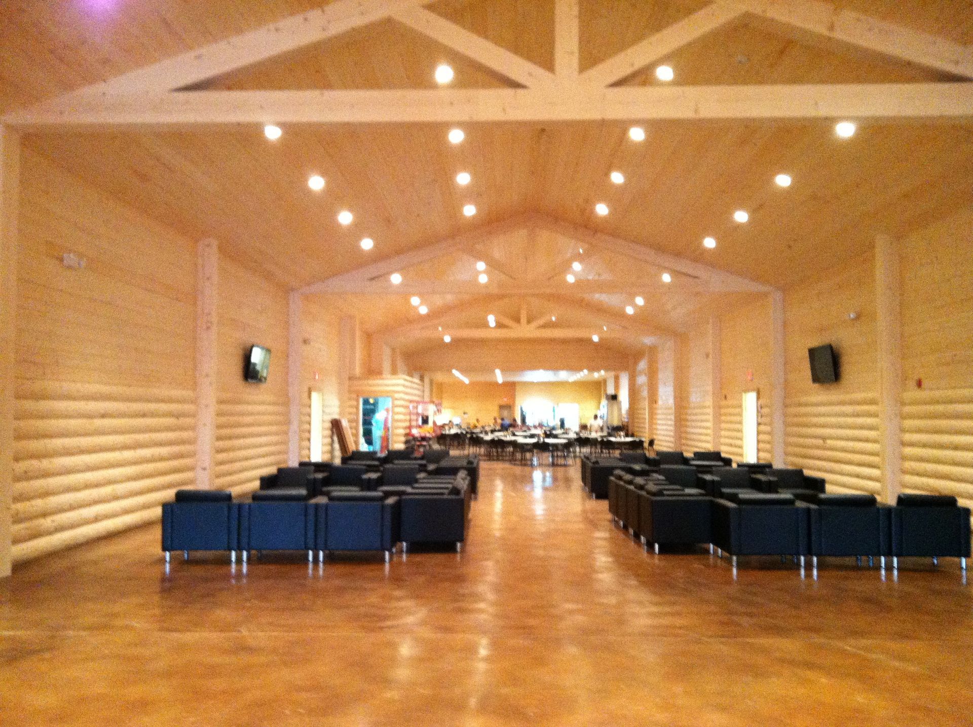 Empty modern hall with wooden walls, rows of blue chairs, and bright ceiling lights