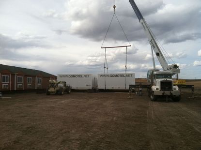 A crane is lifting a white container that says ' cargo ' on it