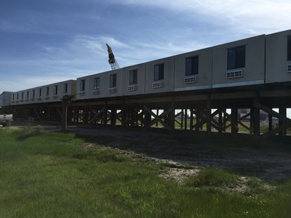 A train is sitting on a bridge over a grassy field