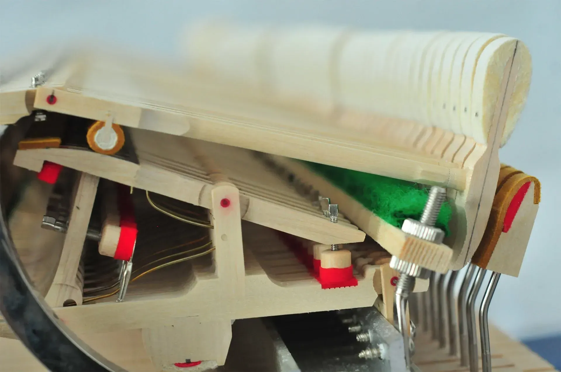 A close up of the inside of a piano with a green cushion