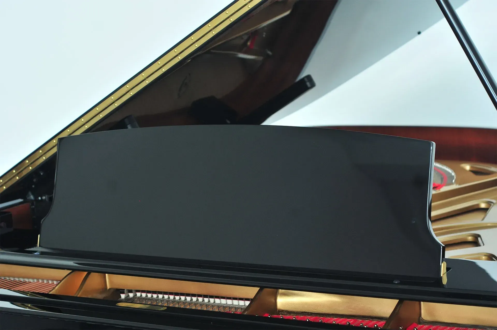 A close up of a black grand piano with the lid open.