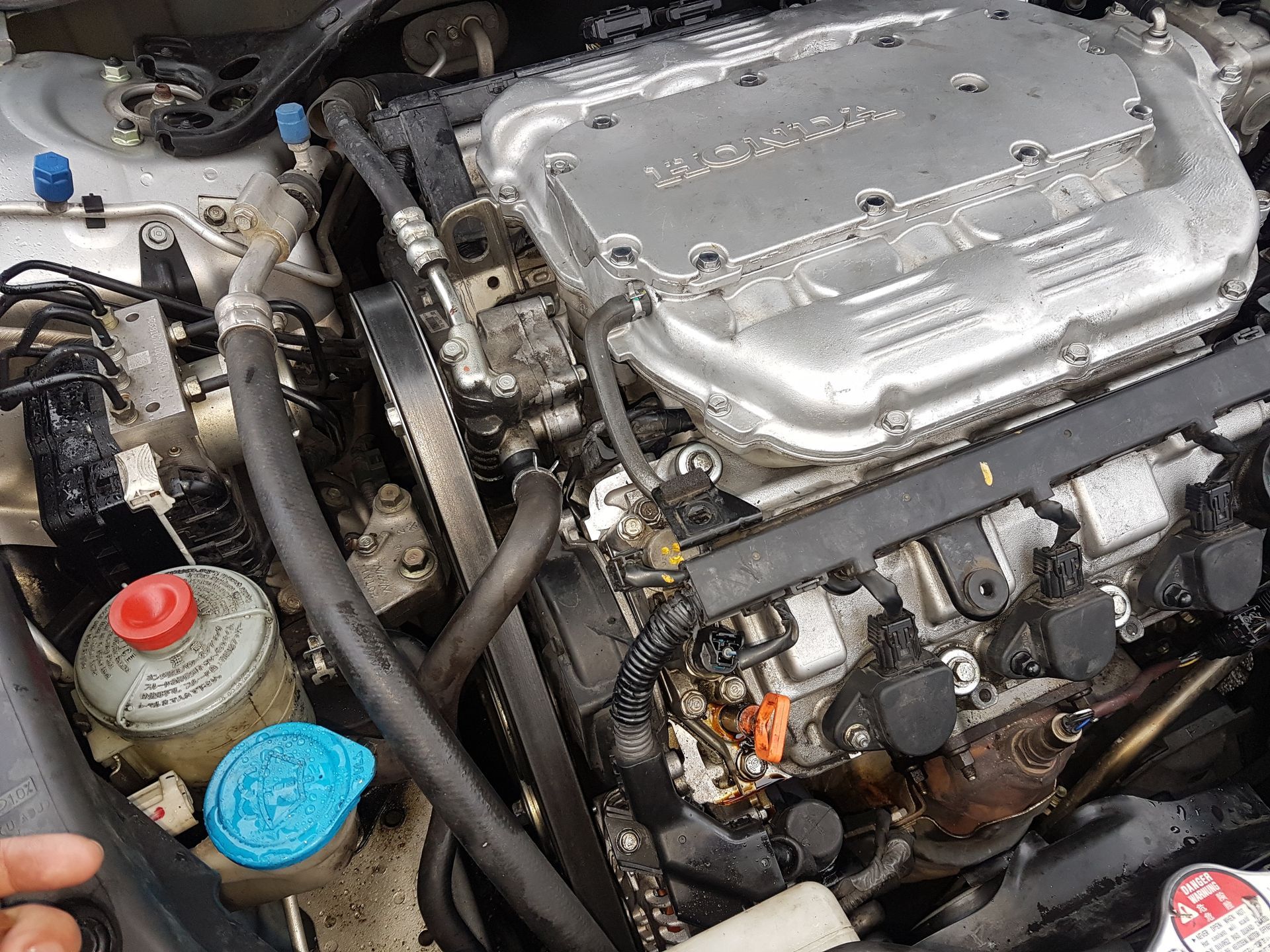 An overhead view of the open engine bay of a Honda vehicle, highlighting mechanical components and fluid reservoirs.