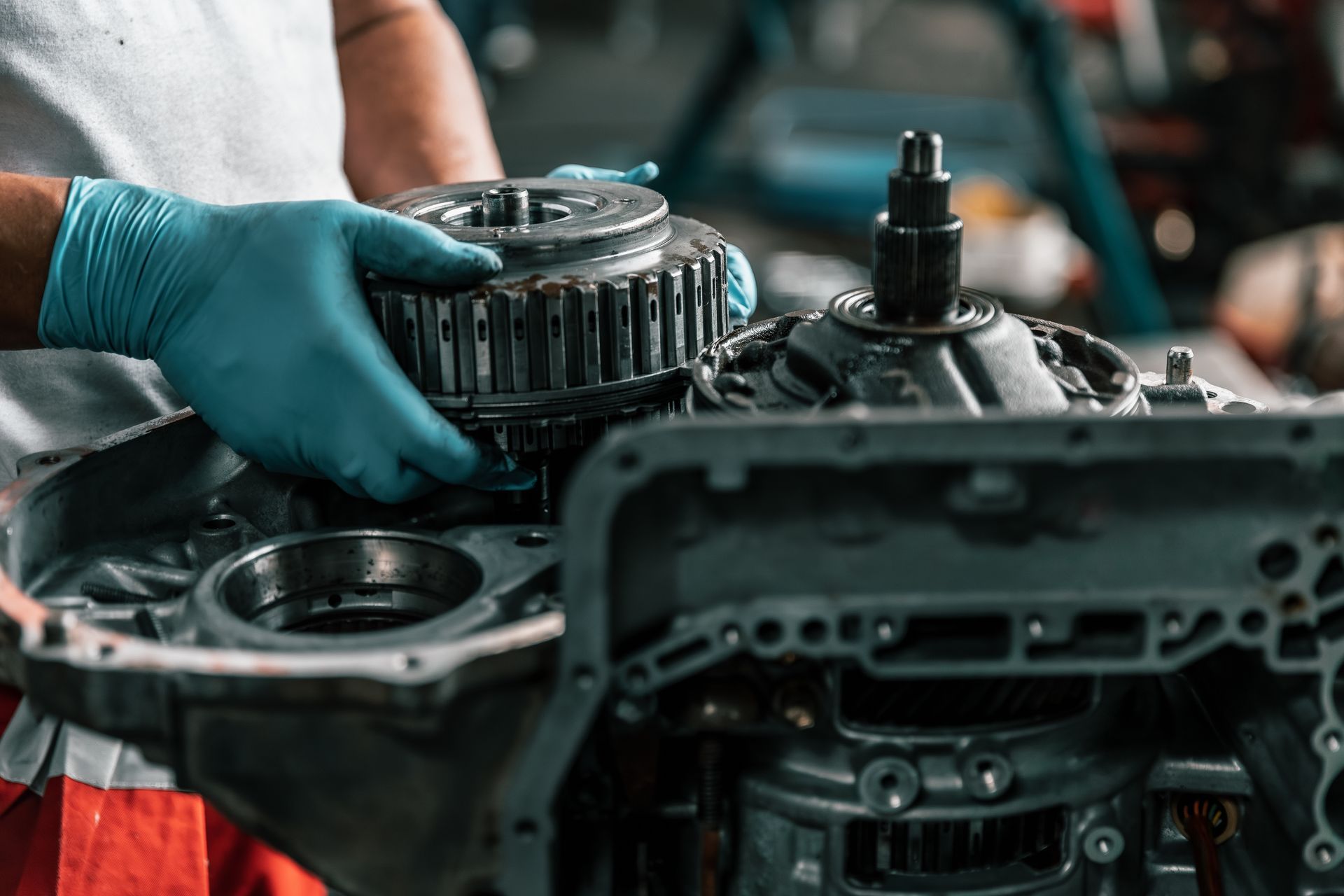 Mechanic wearing blue gloves handling engine parts in a workshop