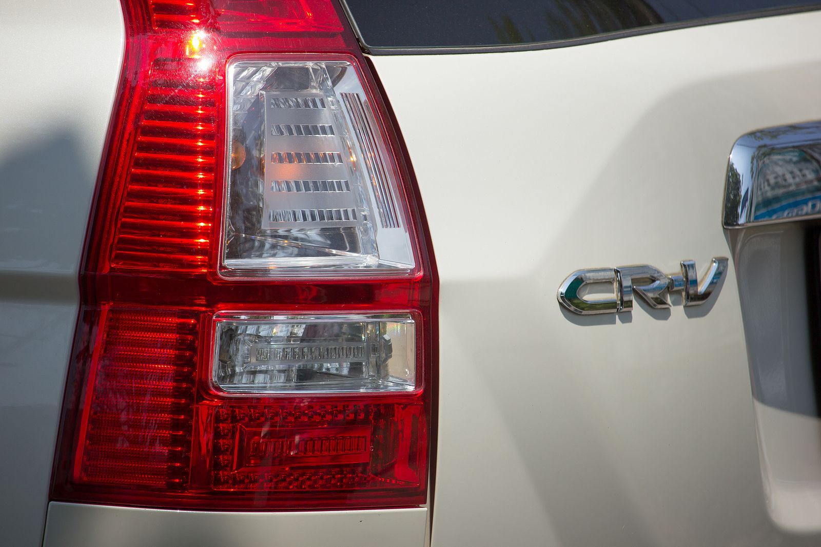 Close-up of a white Honda CRV taillight and the CRV emblem on the vehicle's body.