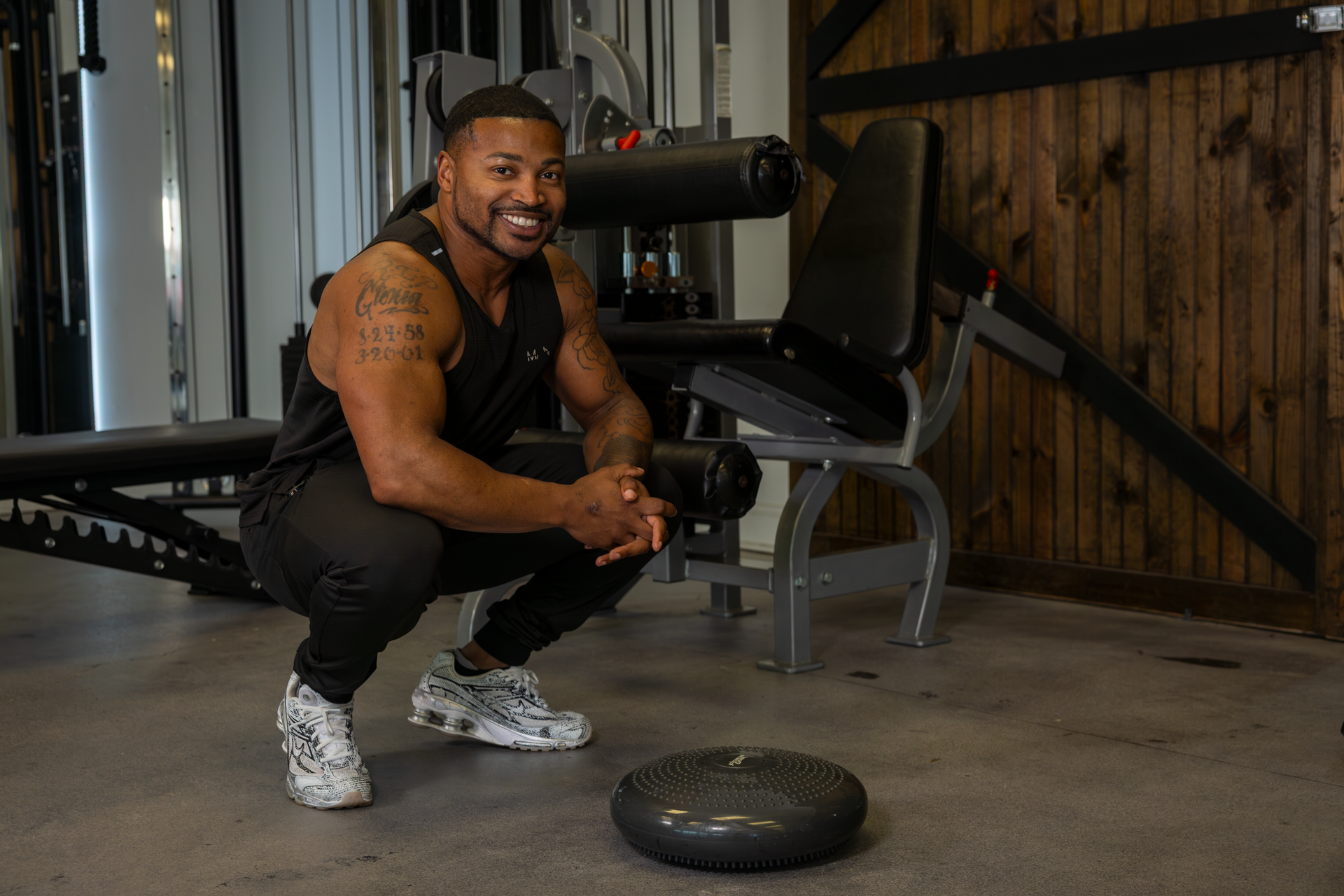 Contact Trey Johnson to build strength and muscle. Trey Johnson in black workout clothes smiling at 360 Image Fitness gym
