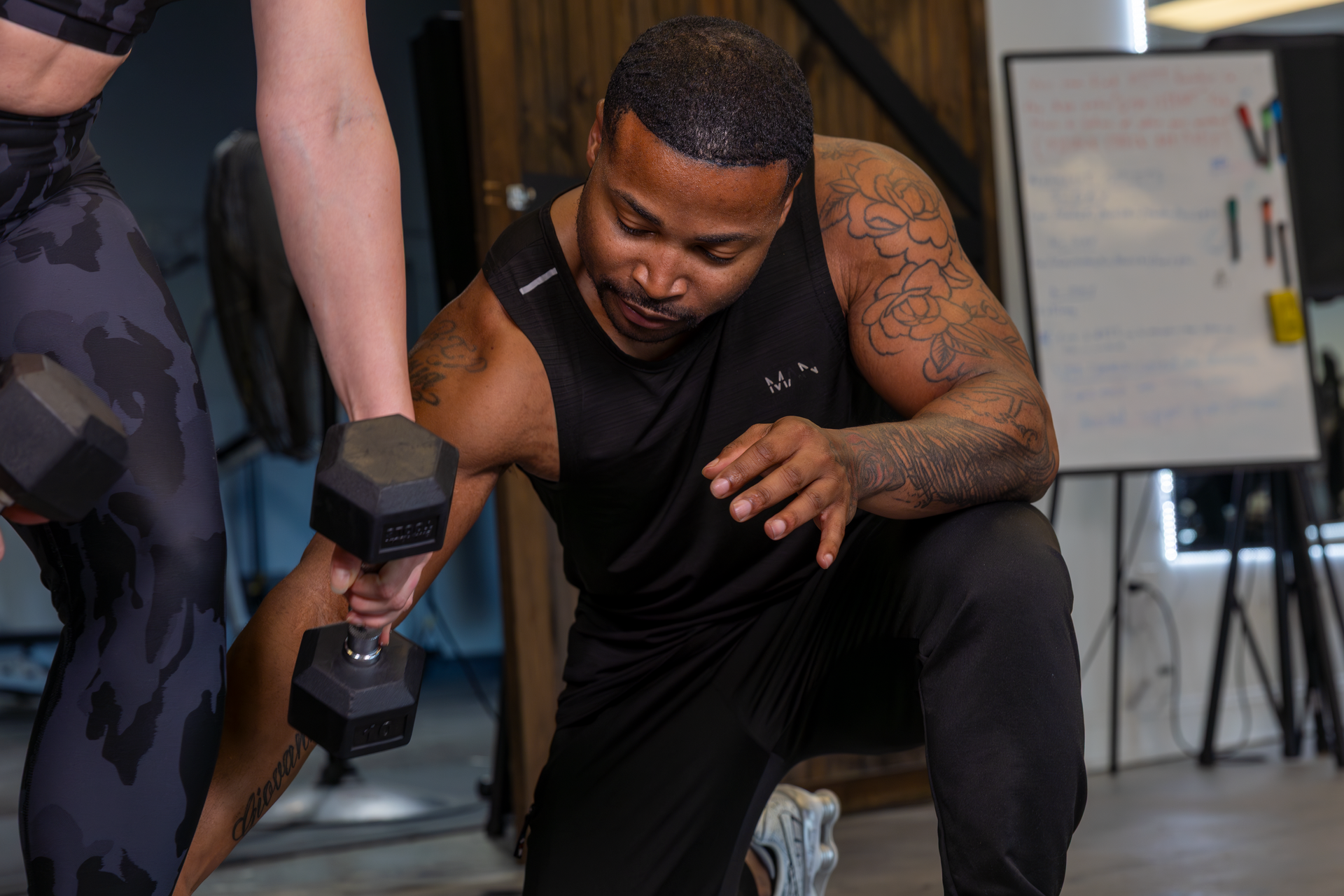 Your Trainer Trey Johnson at 360 Image Fitness in gym assisting a female personal client with leg strengthening exercises