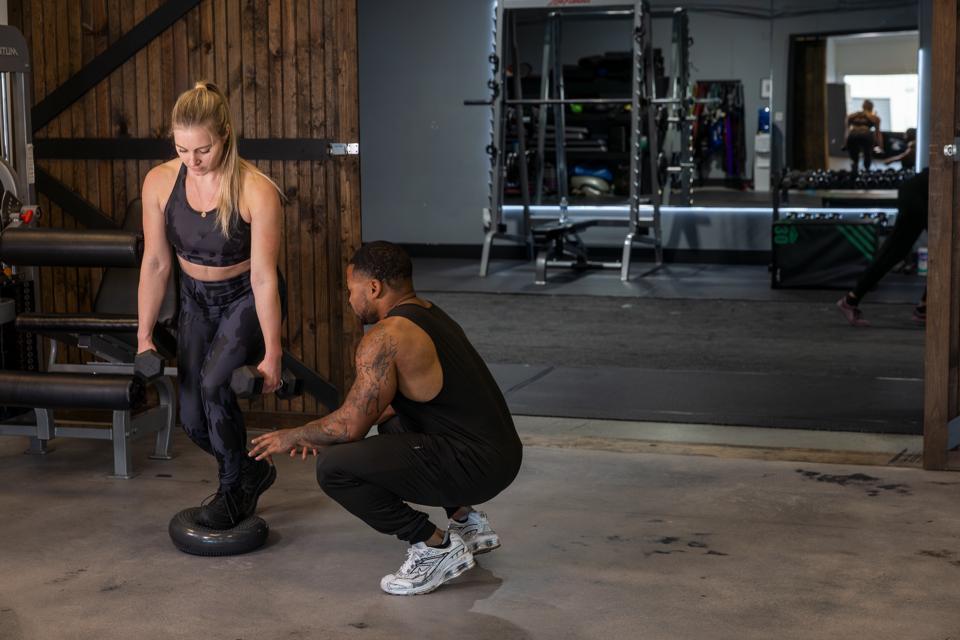 Your Trainer Trey Johnson at 360 Image Fitness in gym assisting a female client with post-injury leg strengthening exercises