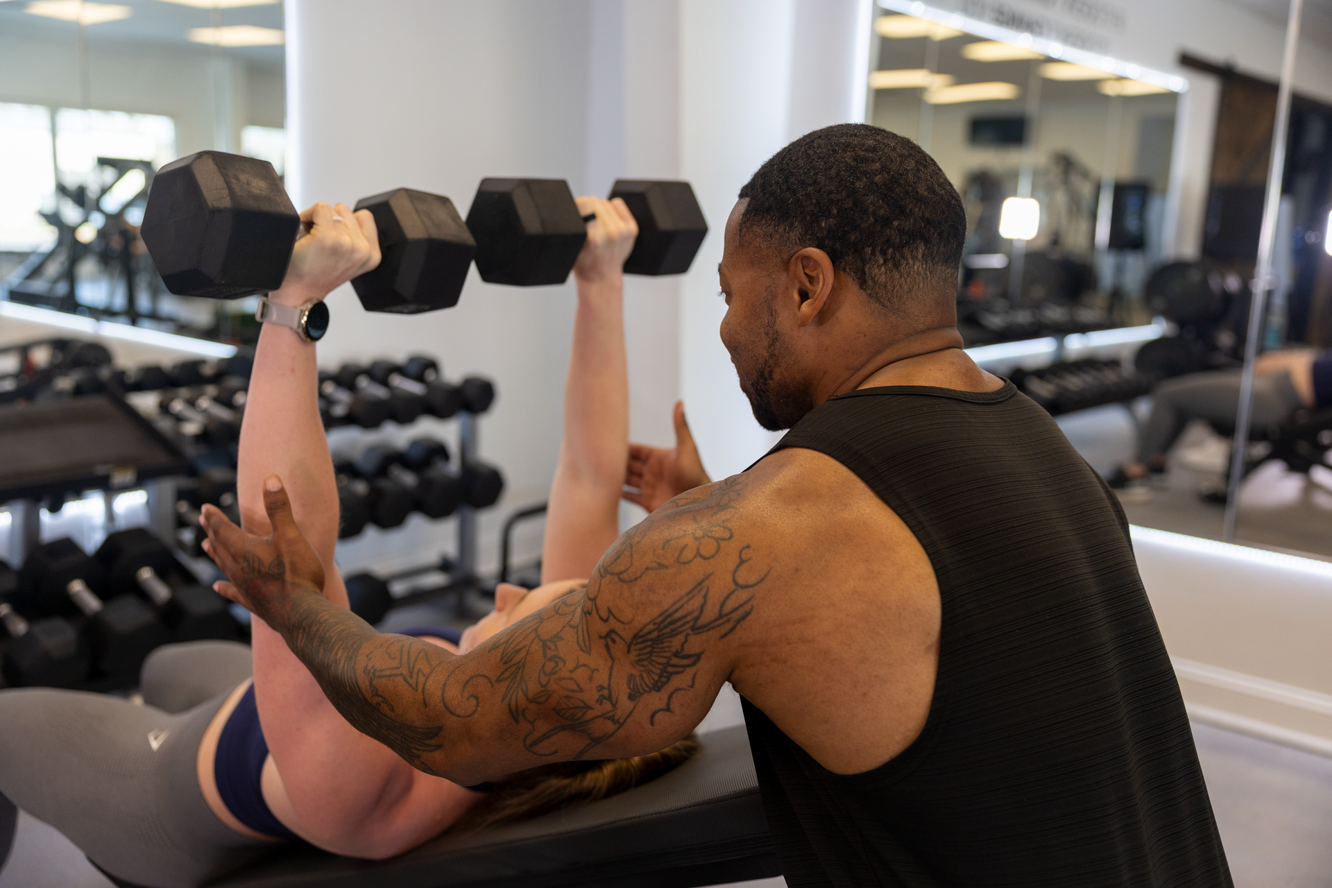 Your Trainer Trey Johnson at 360 Image Fitness in gym spotting a female client with post-injury arm strengthening exercises