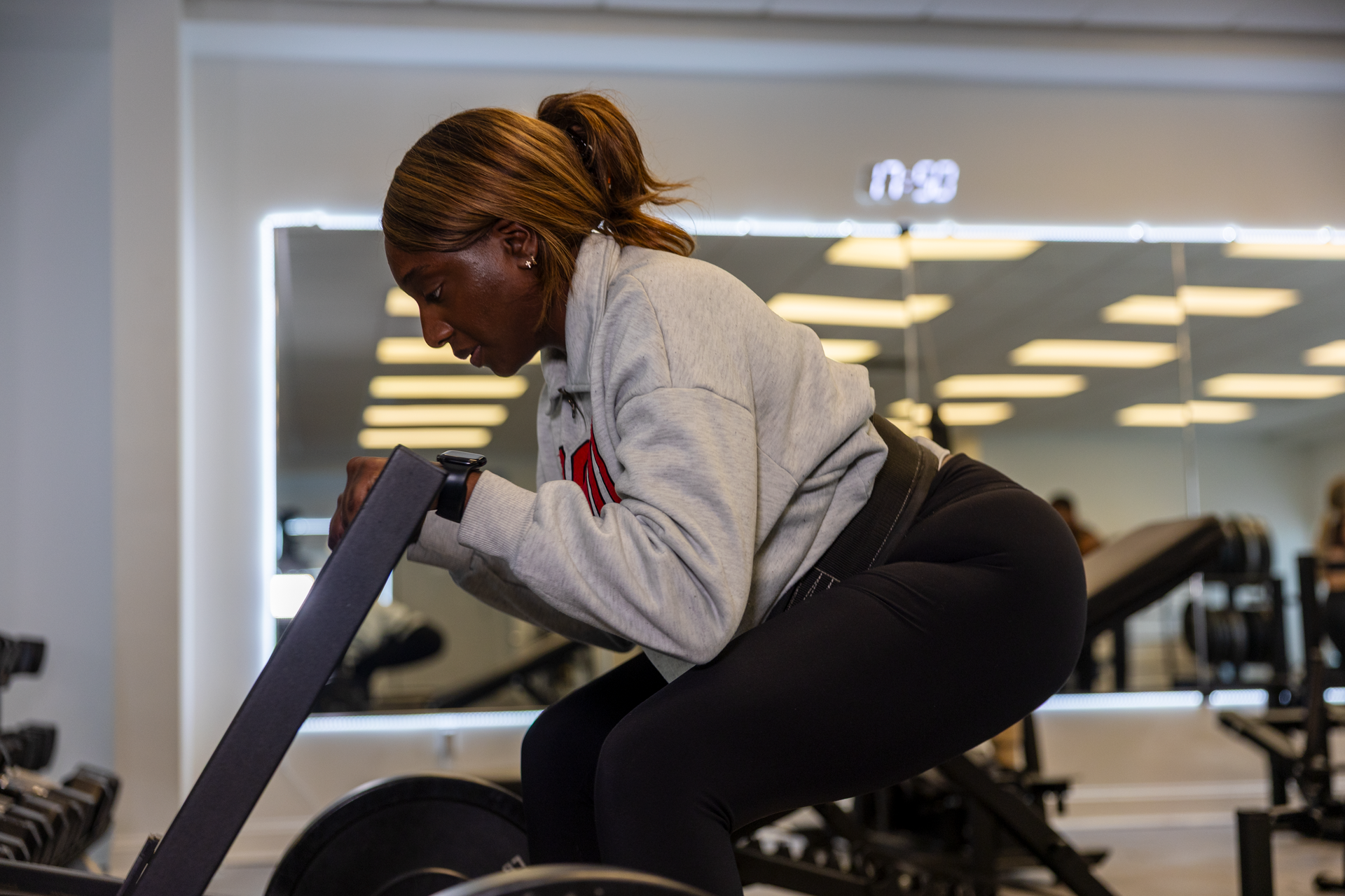 360 image fitness personal training female in sweater client doing squat and leg strength exercises wearing gym clothes