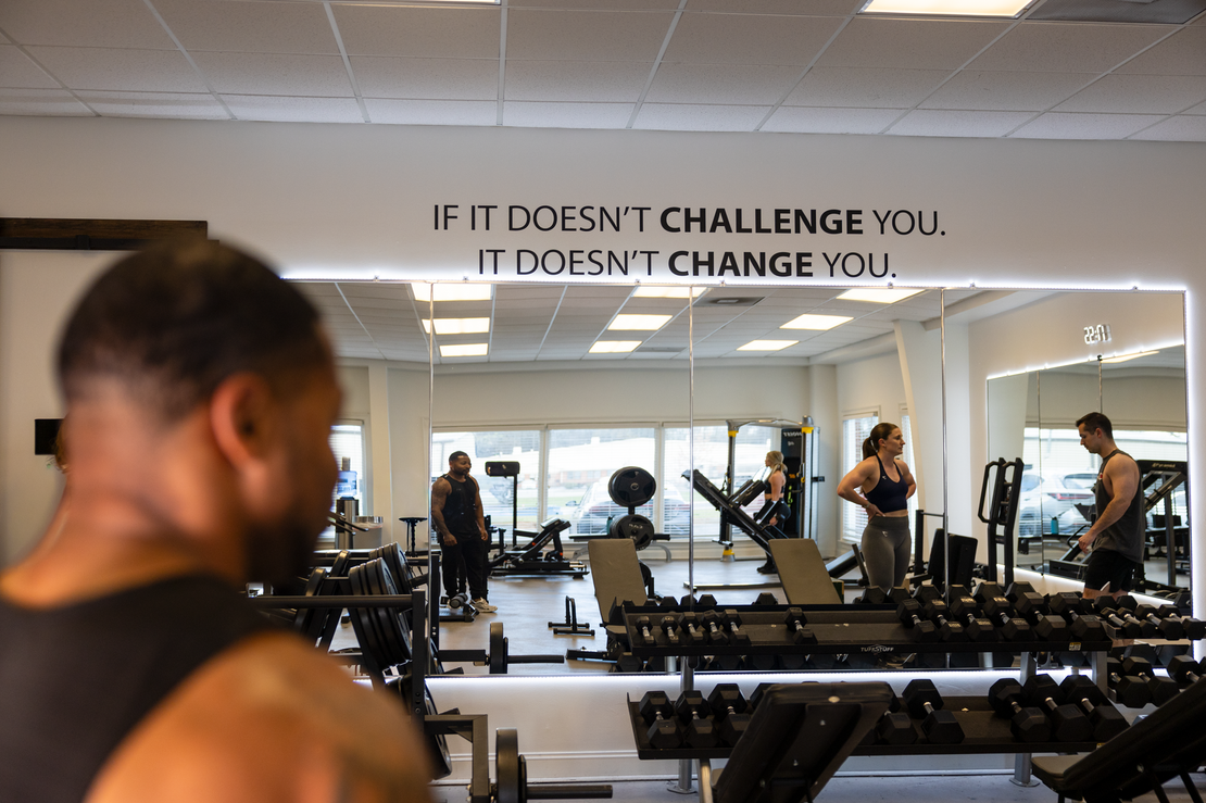 Your Trainer Trey at 360 Image Fitness observing clients in gym at 360 image fitness in watkinsville, ga with sign on wall