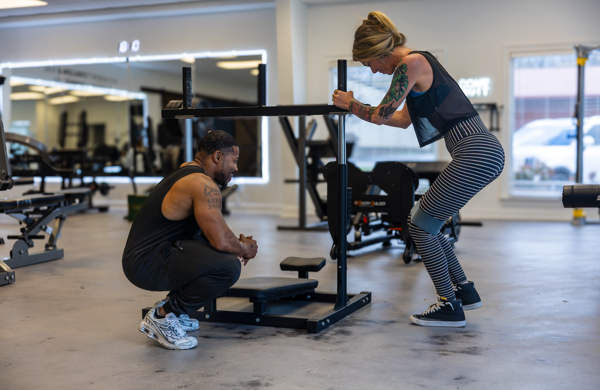 Trainer Trey Johnson at 360 Image Fitness gym in Watkinsville, GA helping female client with leg strength building exercises