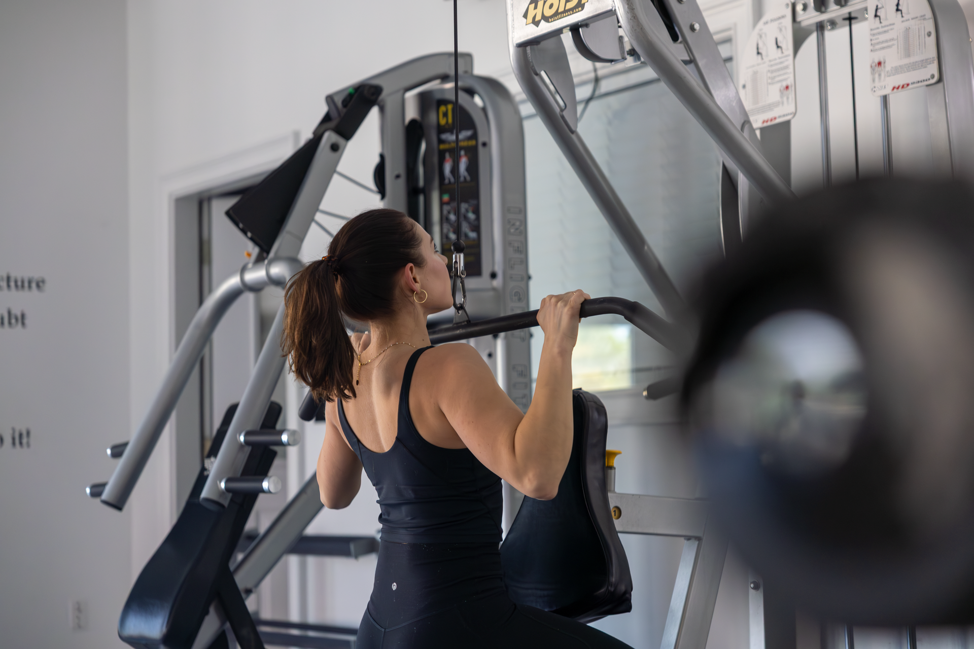 Female with brown hair in all black doing tricep workout at 360 image fitness wearing all black