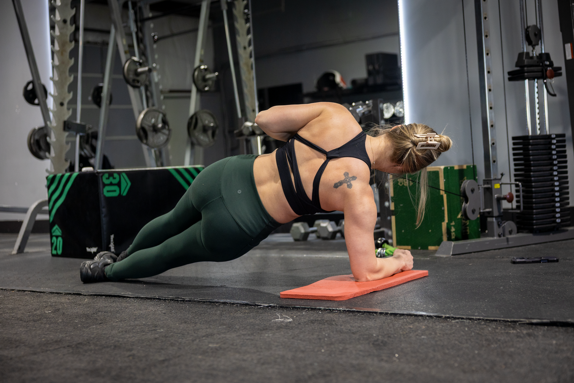 Female in blonde hair in black and grey exercise clothes doing core workout at 360 image fitness surrounded by gym equipment