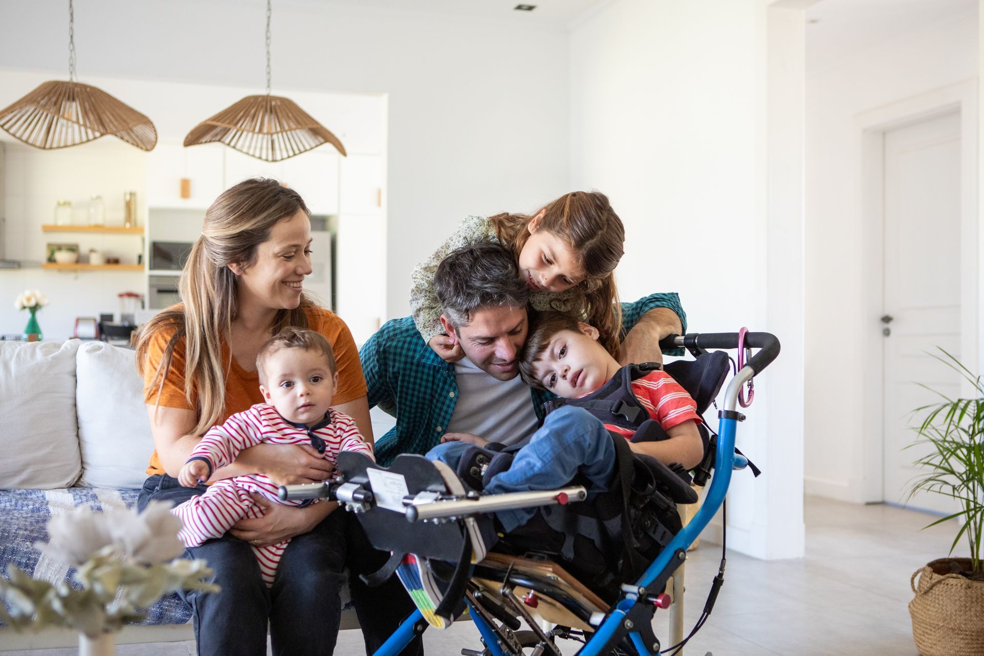 Family gathered around a smiling child in a wheelchair in a bright home kitchen