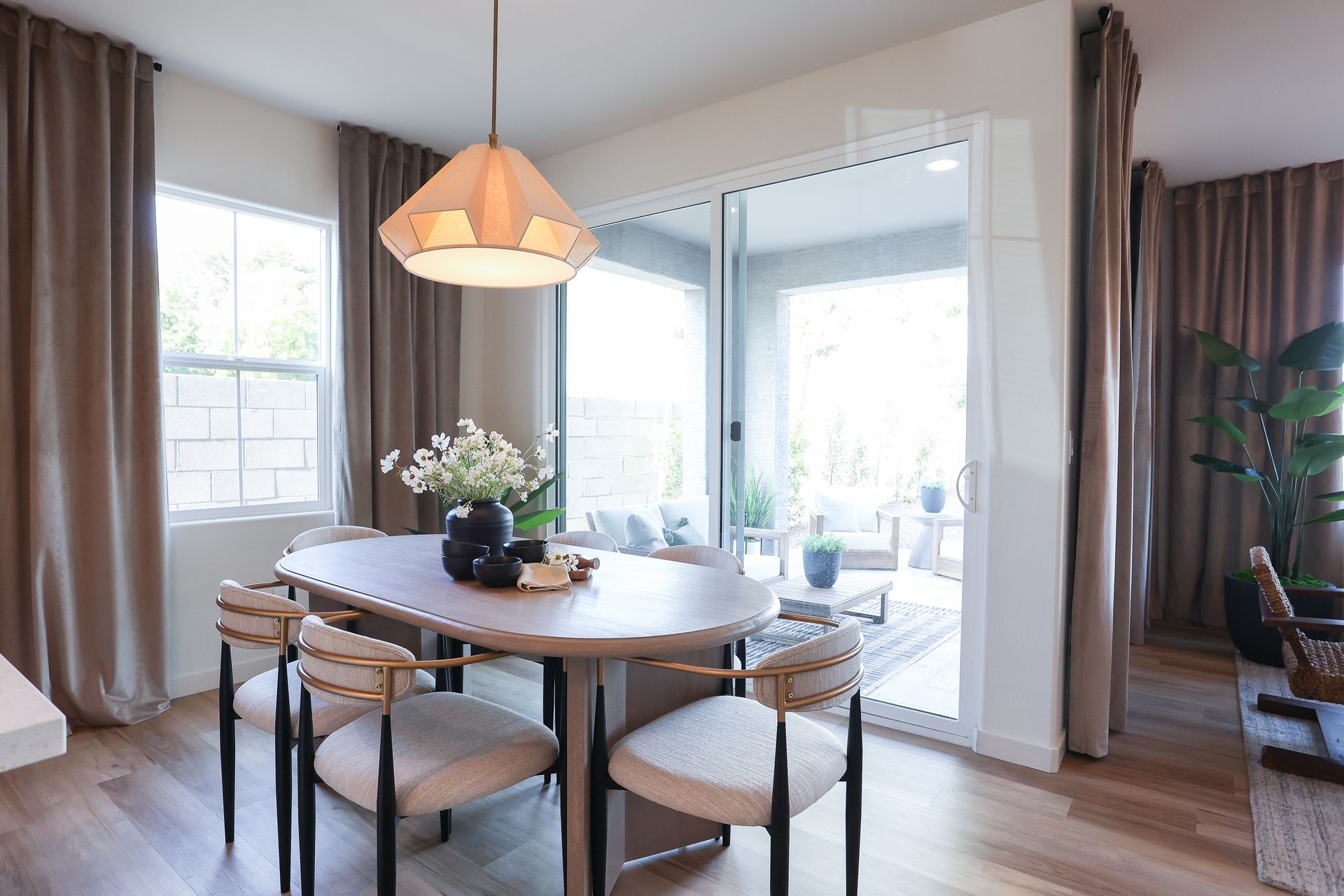 Bright dining room with round table, pendant light, chairs, and sliding glass doors to a patio.