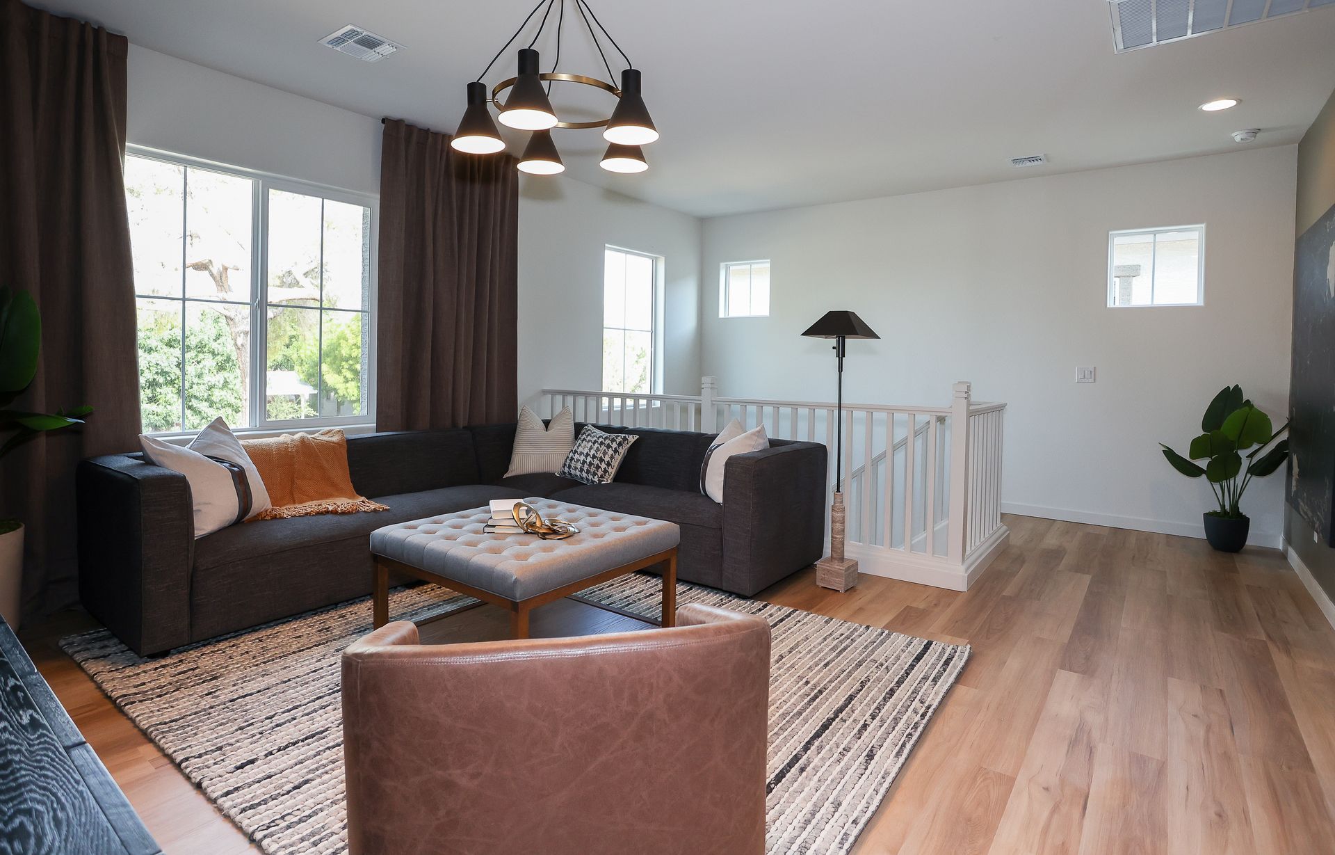 Bright modern living room with sectional sofa, coffee table, rug, and hardwood floors