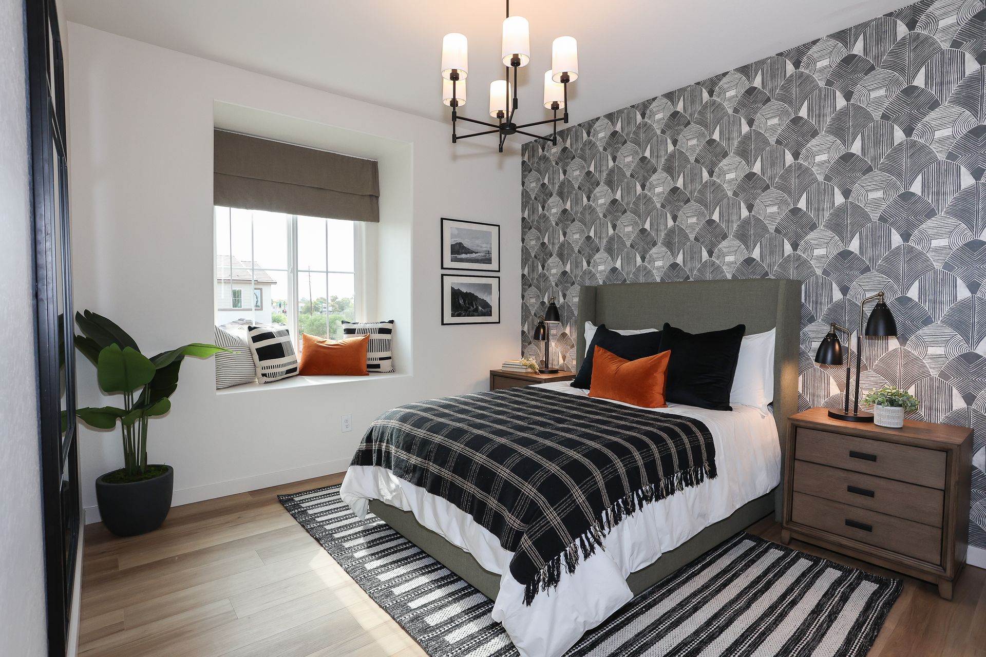 Modern bedroom with black-and-white patterned wallpaper, bed, chandelier, and window seat