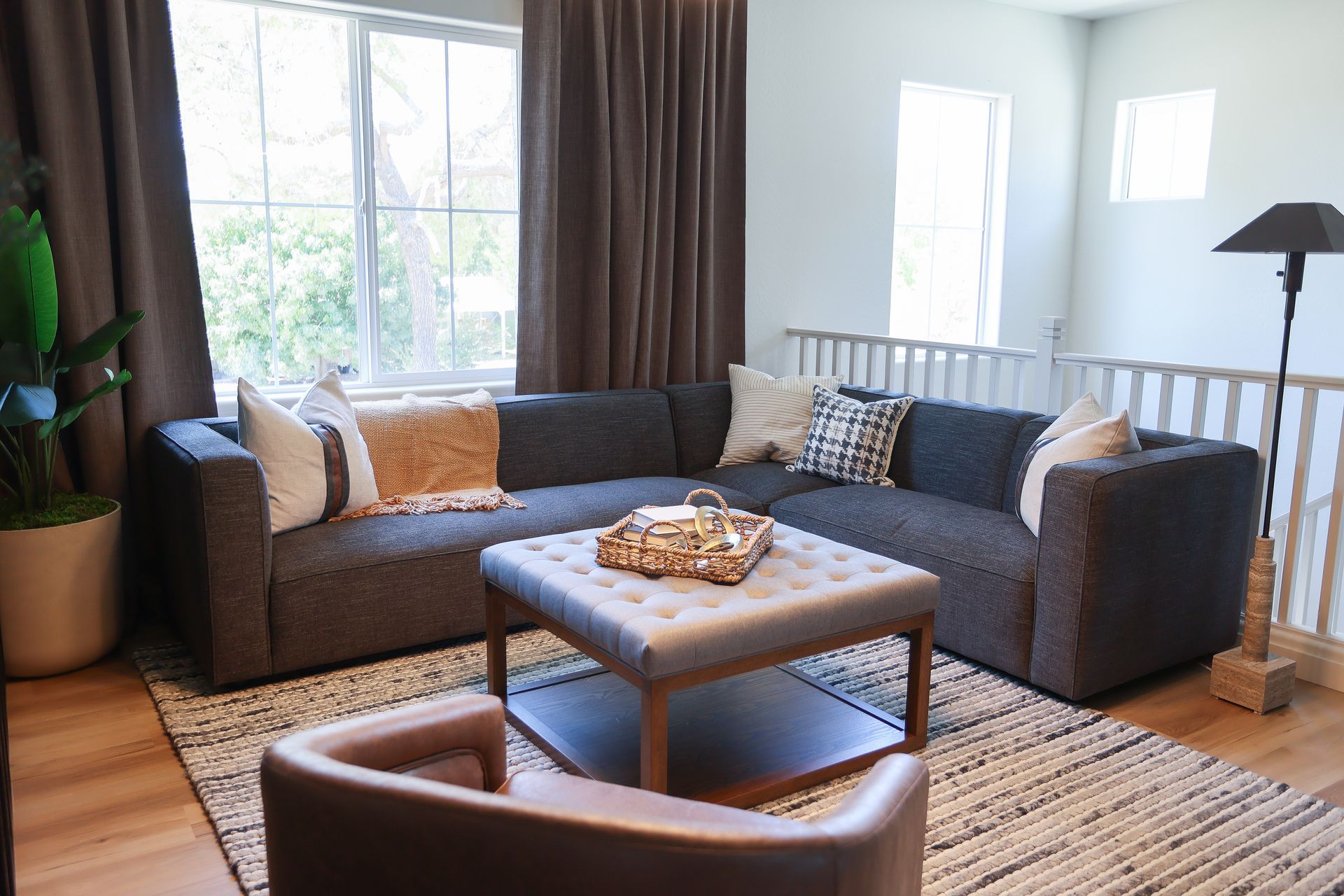 Cozy living room with gray sectional sofa, coffee table, rug, floor lamp, and large windows