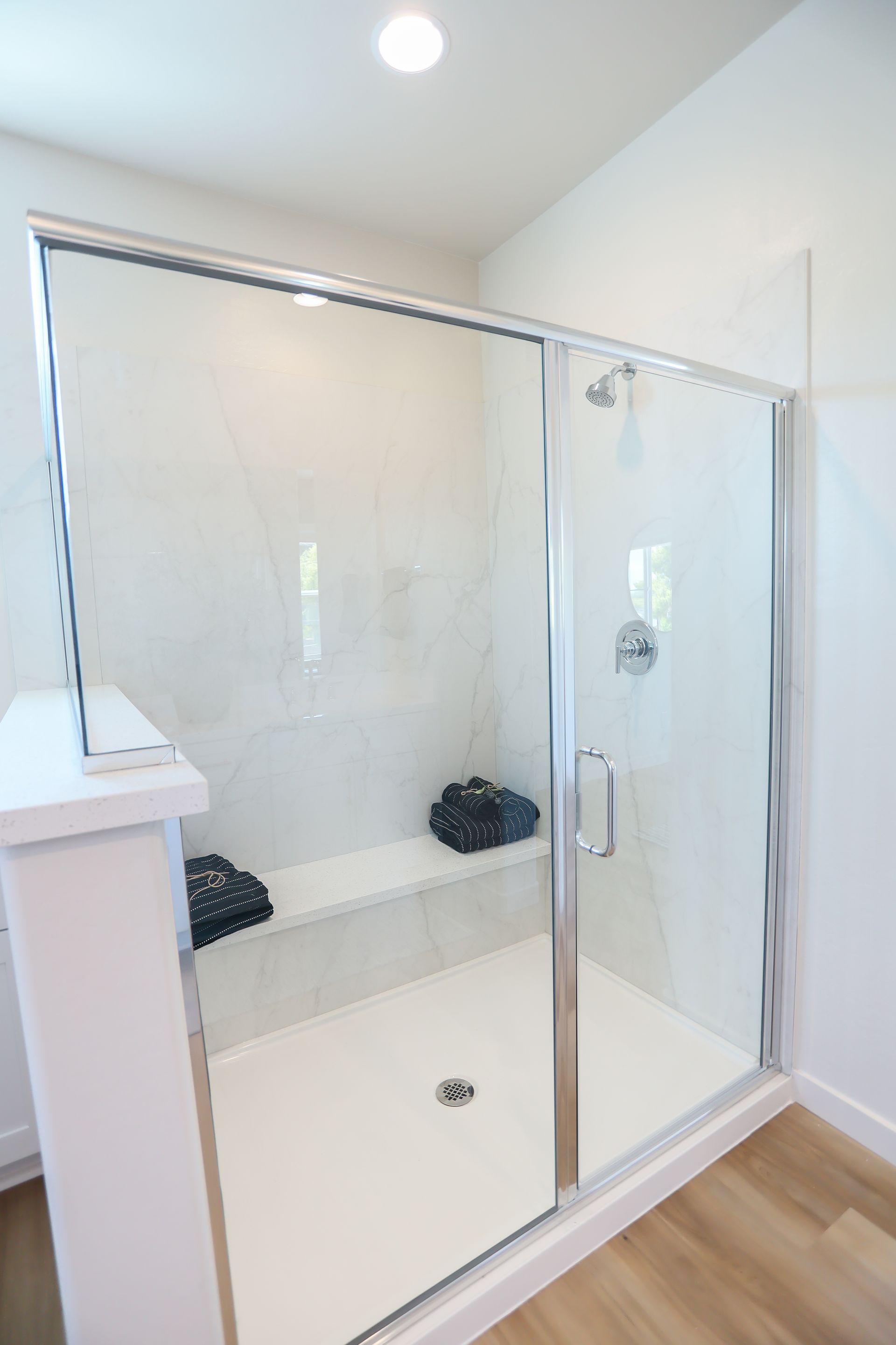 Glass walk-in shower with chrome fixtures and white walls in a modern bathroom