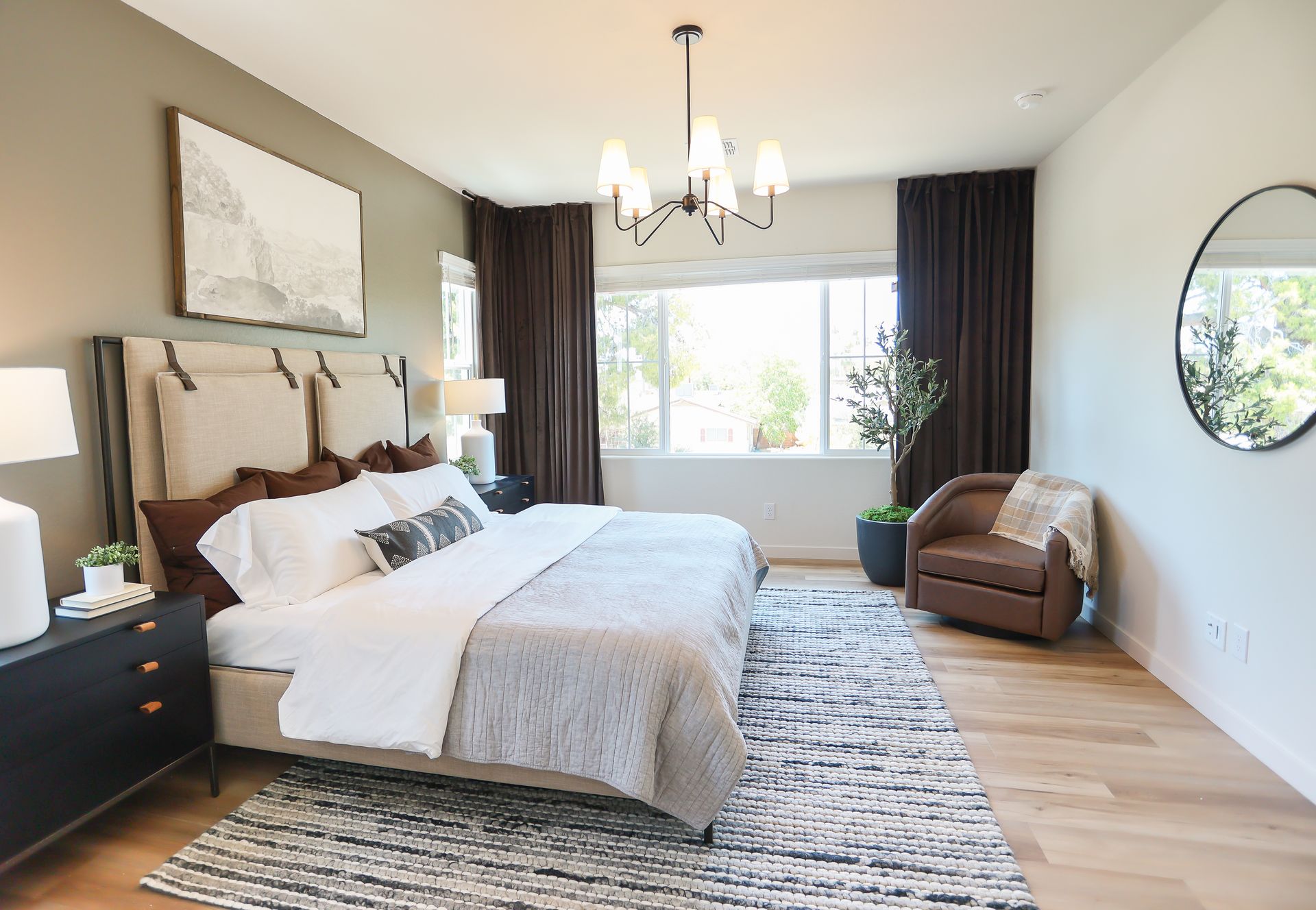 Bright modern bedroom with a bed, bench, chandelier, window, and dark curtains