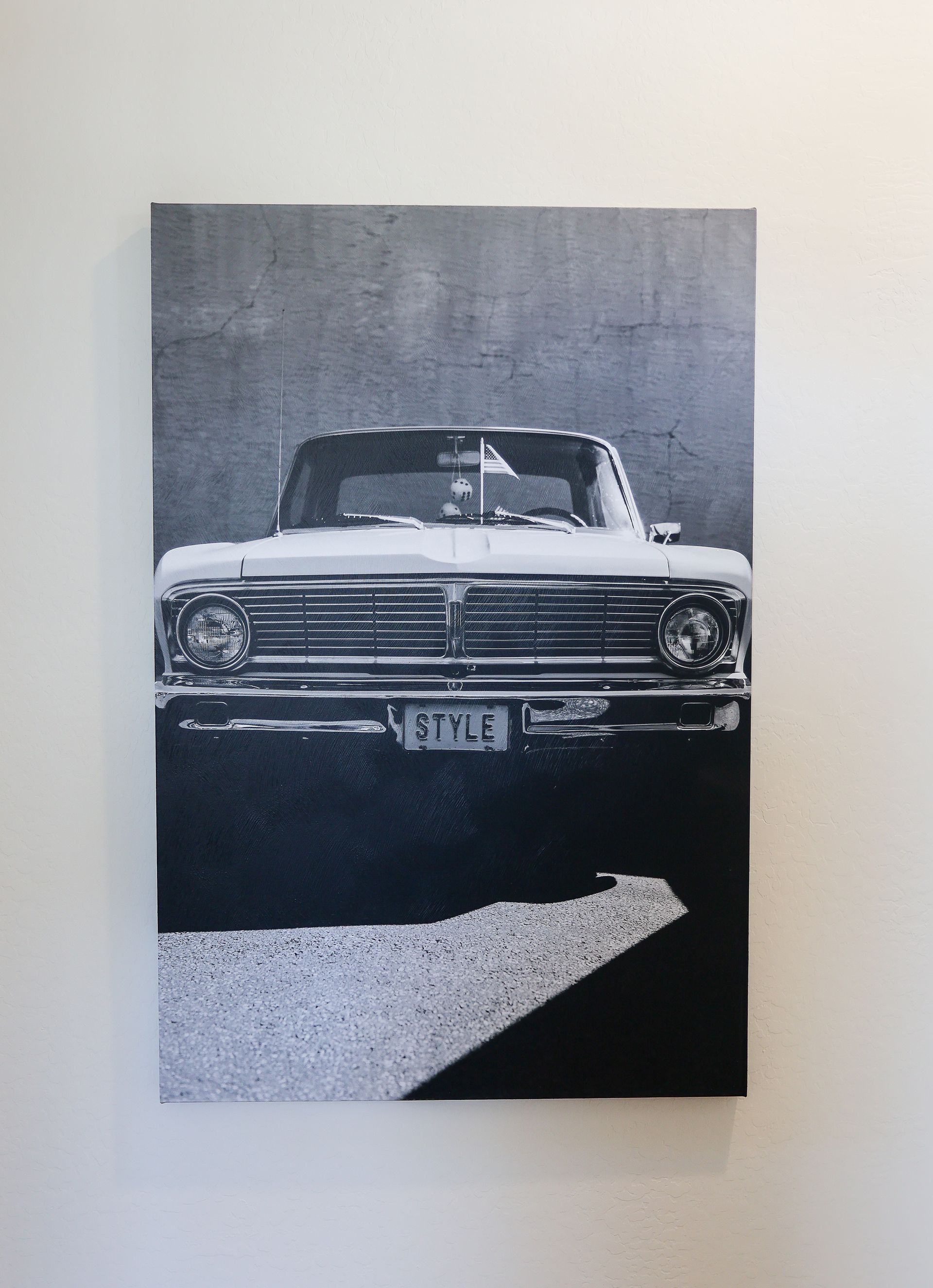 Black-and-white photo of a classic car on display against a plain wall.