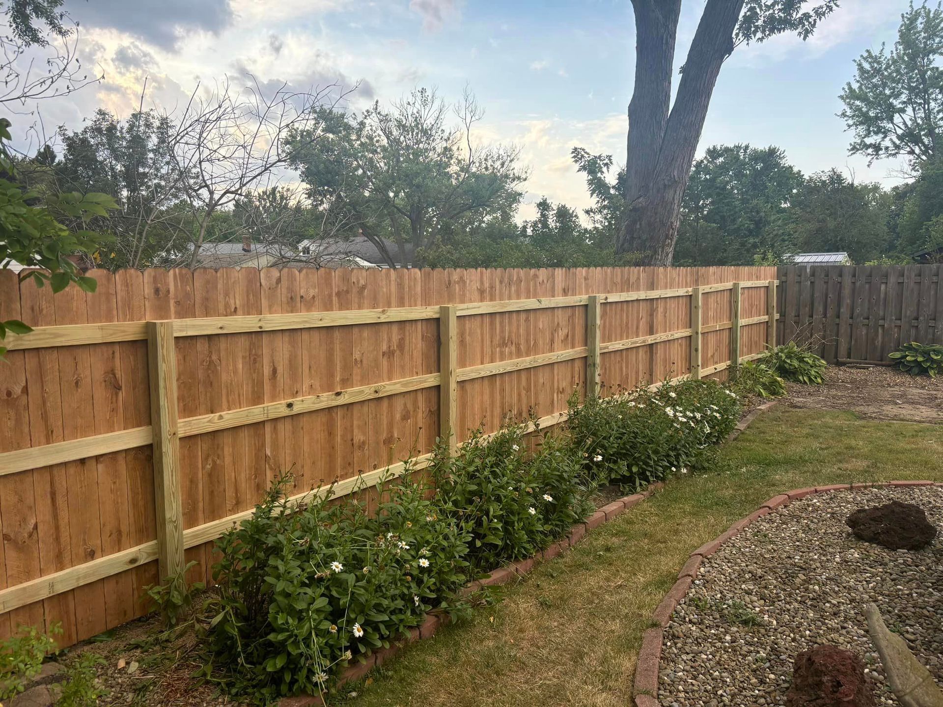A wooden fence is in the backyard of a house.