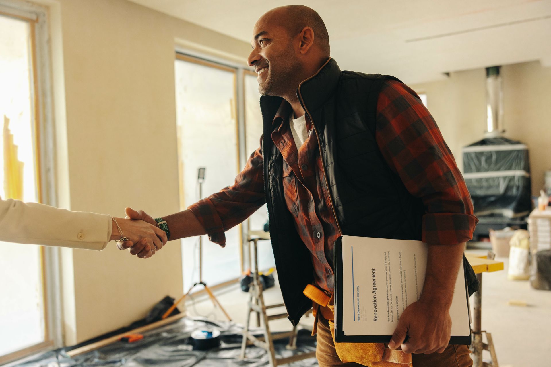 Local general contractor shaking hands with homeowner during home renovation consultation indoors.
