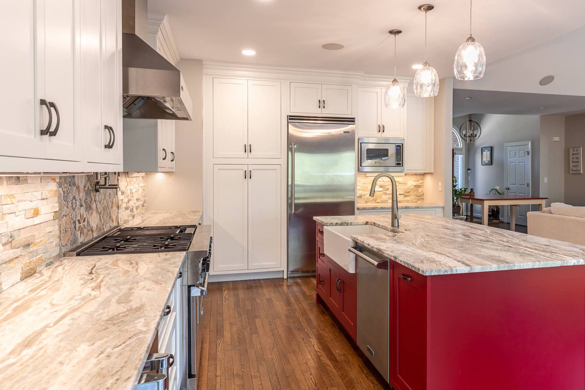 Bright modern kitchen with red island, white cabinets, stainless appliances, and wood floors
