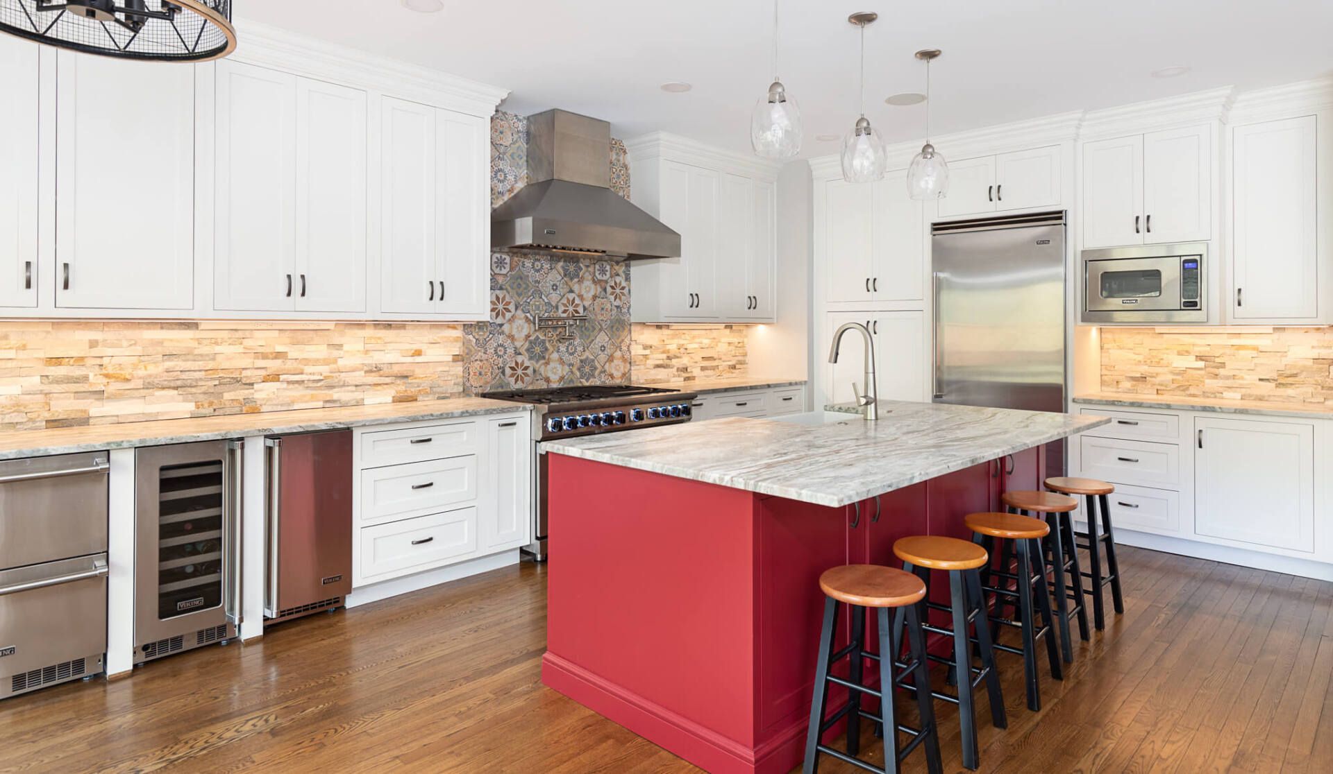 Modern kitchen with white cabinets, red island, stainless appliances, and wood floors