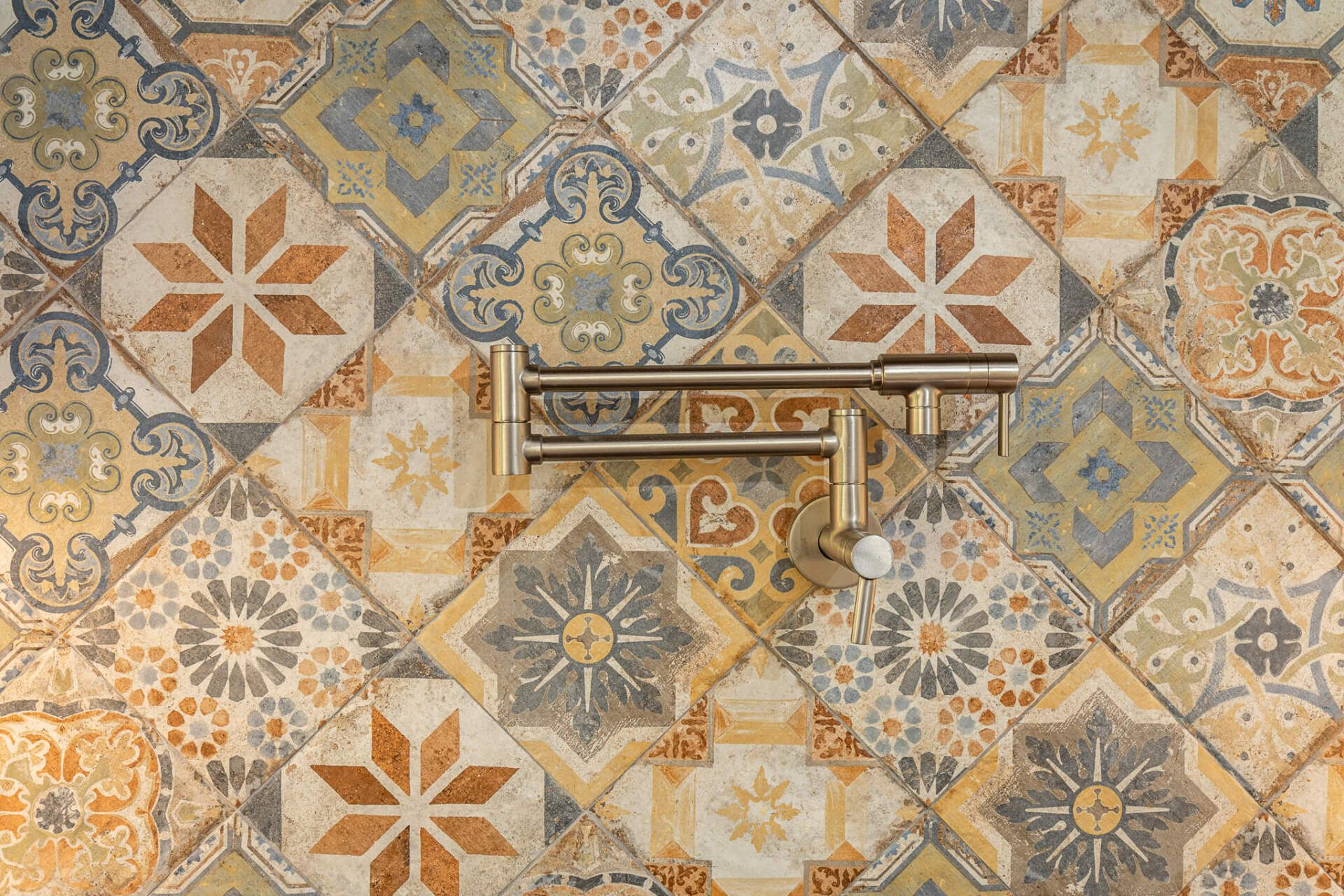 Patterned ceramic tile wall with beige, blue, and orange star designs and a metal handle in the center