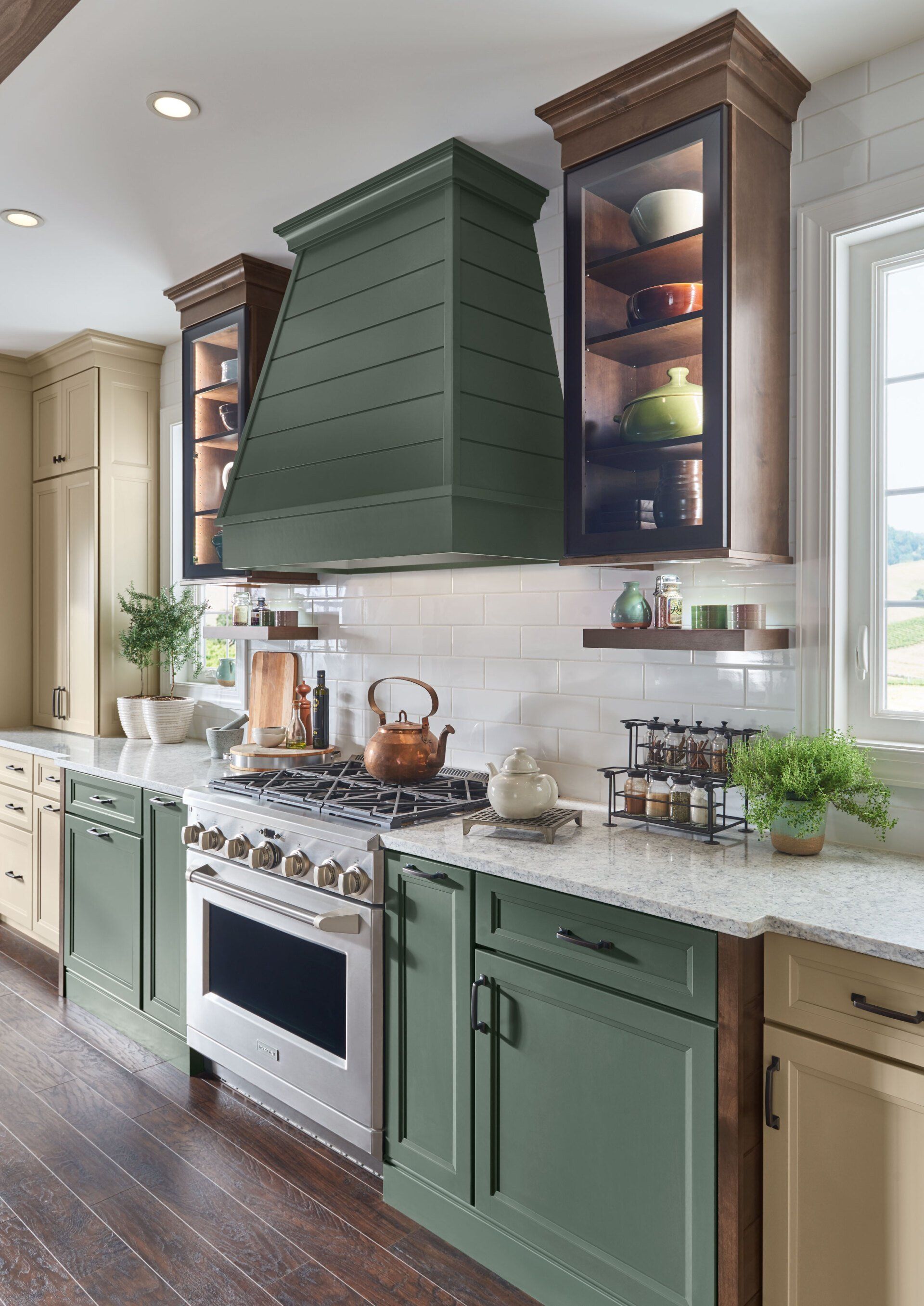 Modern kitchen with sage green cabinets, white countertops, stainless stove, and dark wood floors