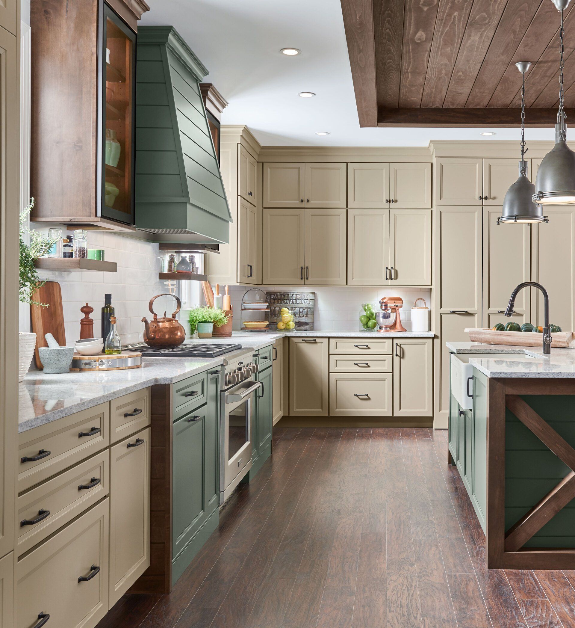 Bright farmhouse kitchen with cream cabinets, green range, wood floors, and white marble island.