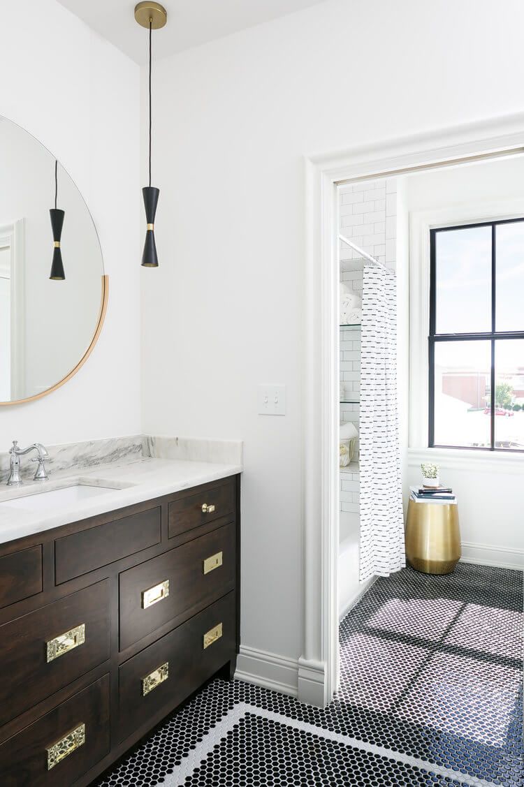Modern bathroom with dark vanity, round mirror, and tiled shower doorway with a black-framed window