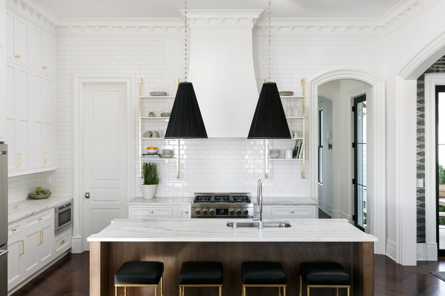 Bright white modern kitchen with marble island, black pendant lights, and dark stools