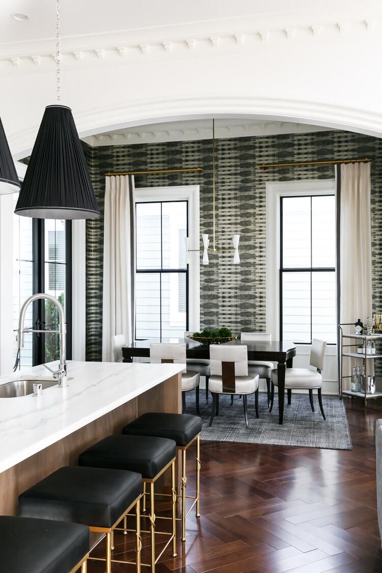 Stylish dining room with green striped curtains, tall windows, black chairs, and a white kitchen island