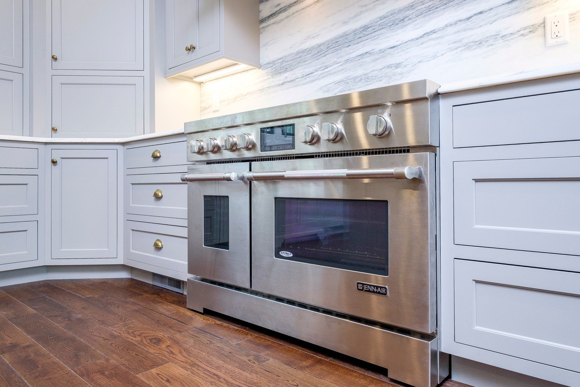Modern kitchen with stainless steel oven, white cabinets, and dark wood floors