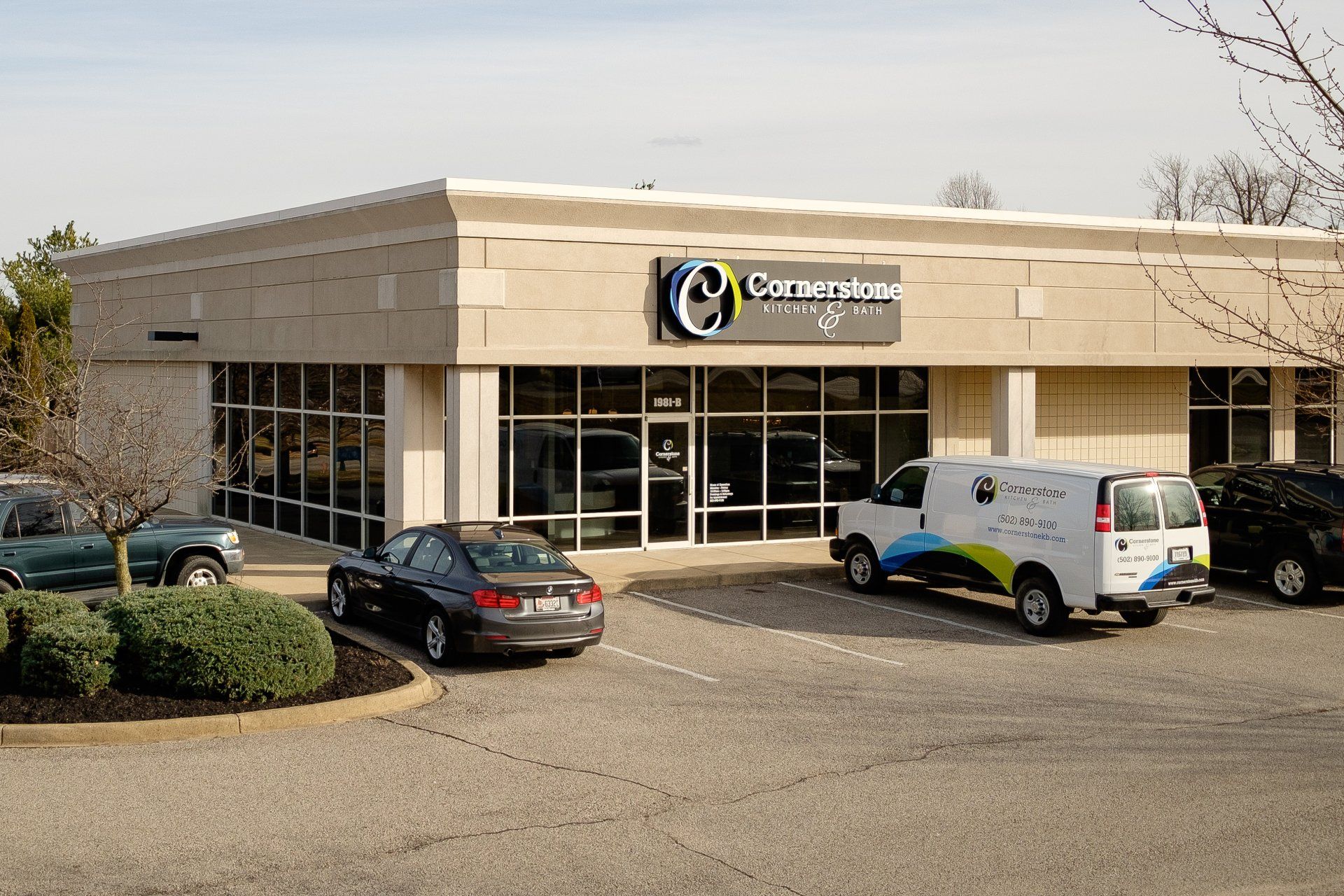 Commercial building exterior with parked cars and a white van in front