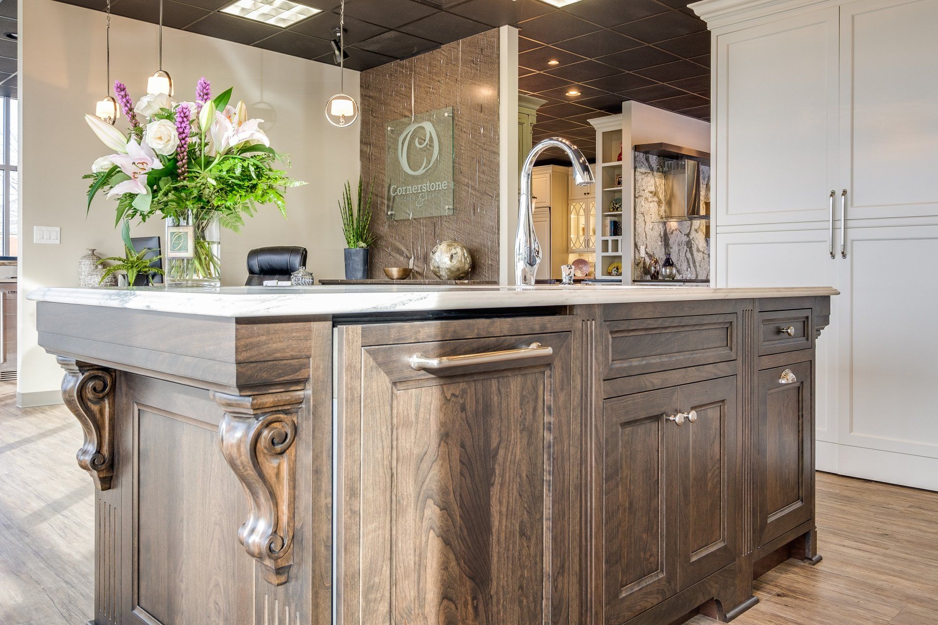Modern kitchen island with stone countertop, wood cabinets, and a vase of flowers