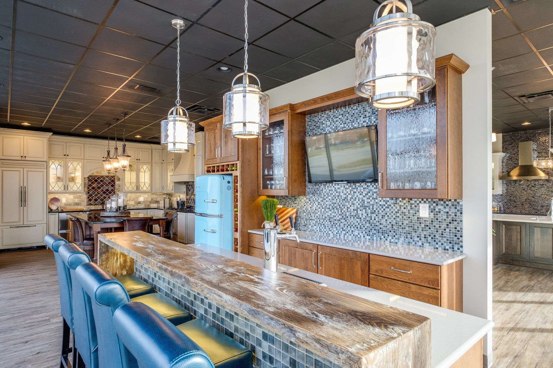 Modern kitchen with blue bar stools, marble island, pendant lights, and a tiled backsplash