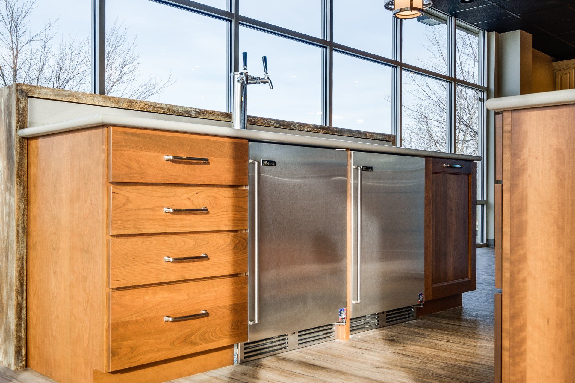 Modern kitchen island with wood drawers, stainless steel cabinets, and a large window view