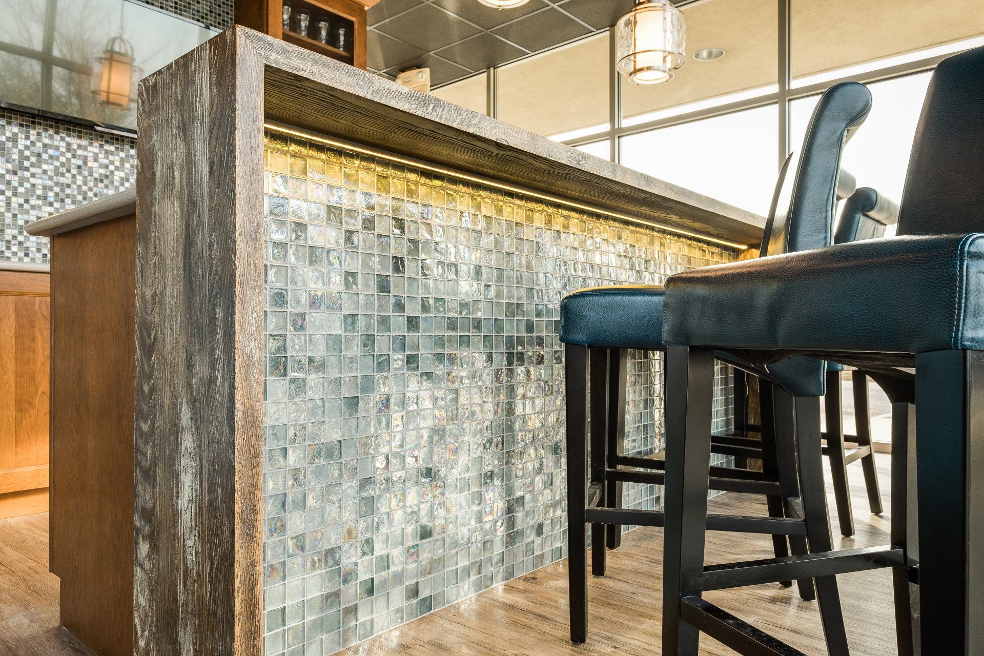 Mosaic-tiled bar counter with dark blue stools in a bright modern café interior
